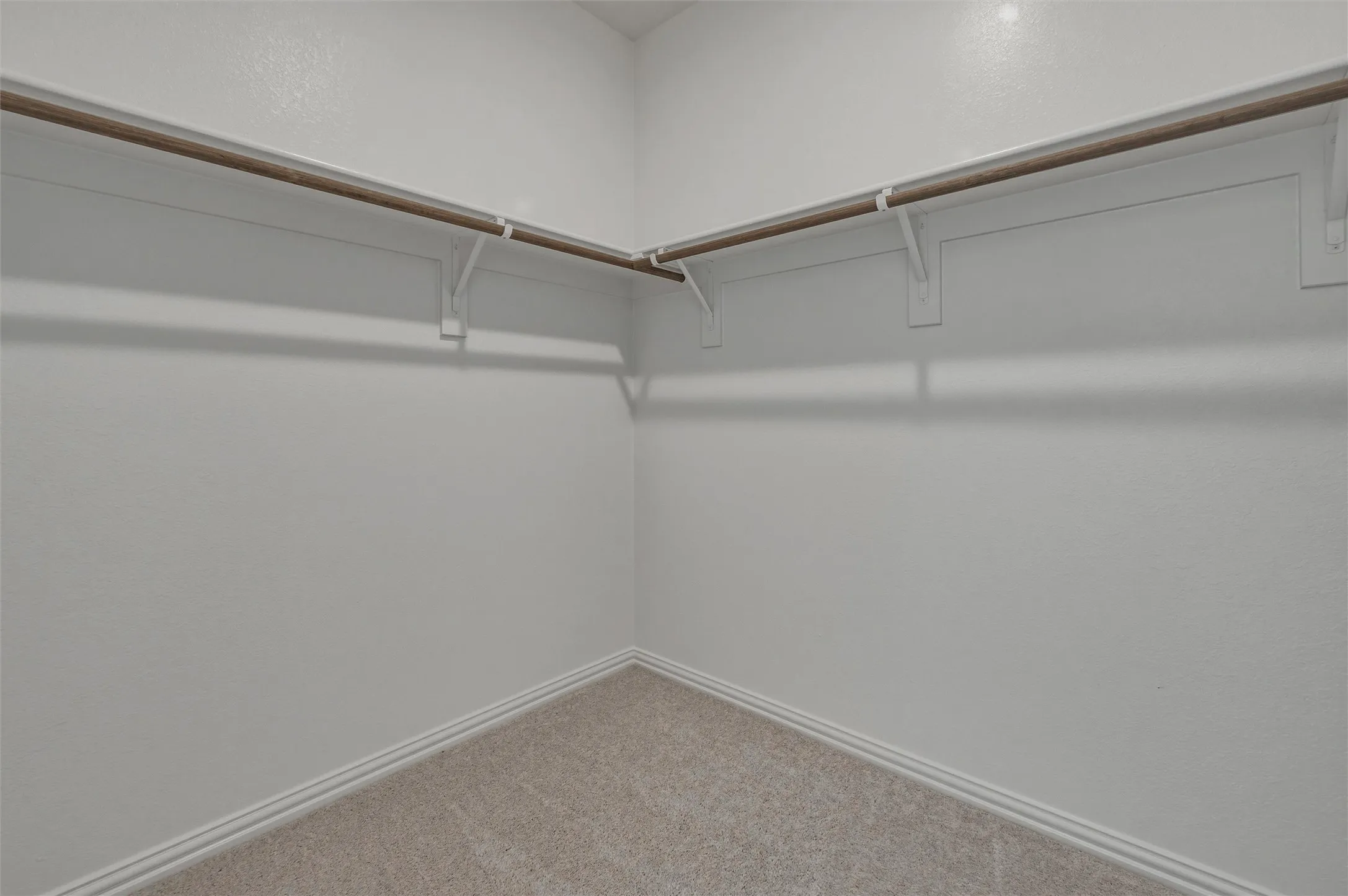Corner closet with neutral carpeting and a built-in shelving system