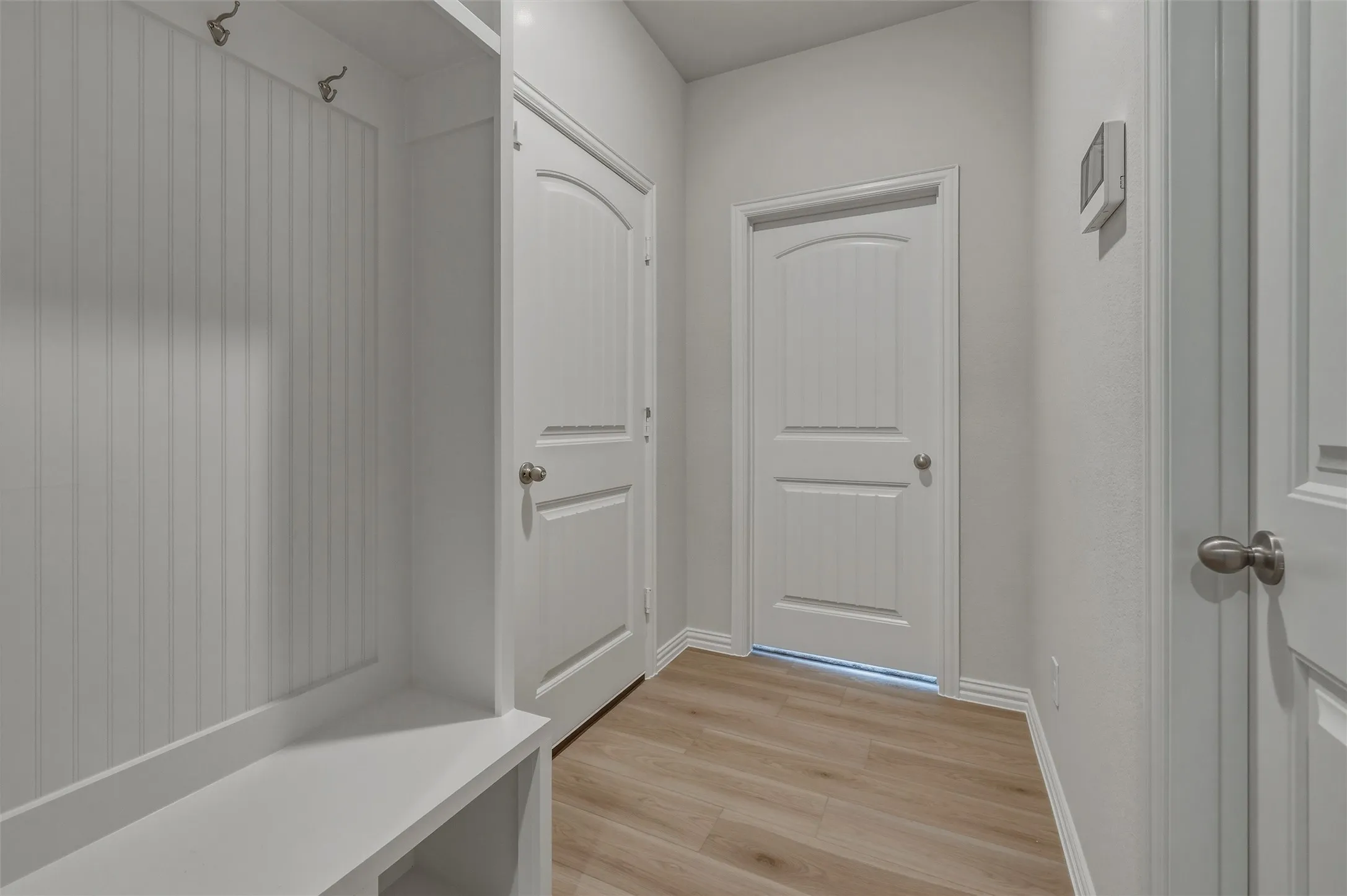 Entryway featuring built-in bench seating, beadboard paneling, and wood-finish flooring