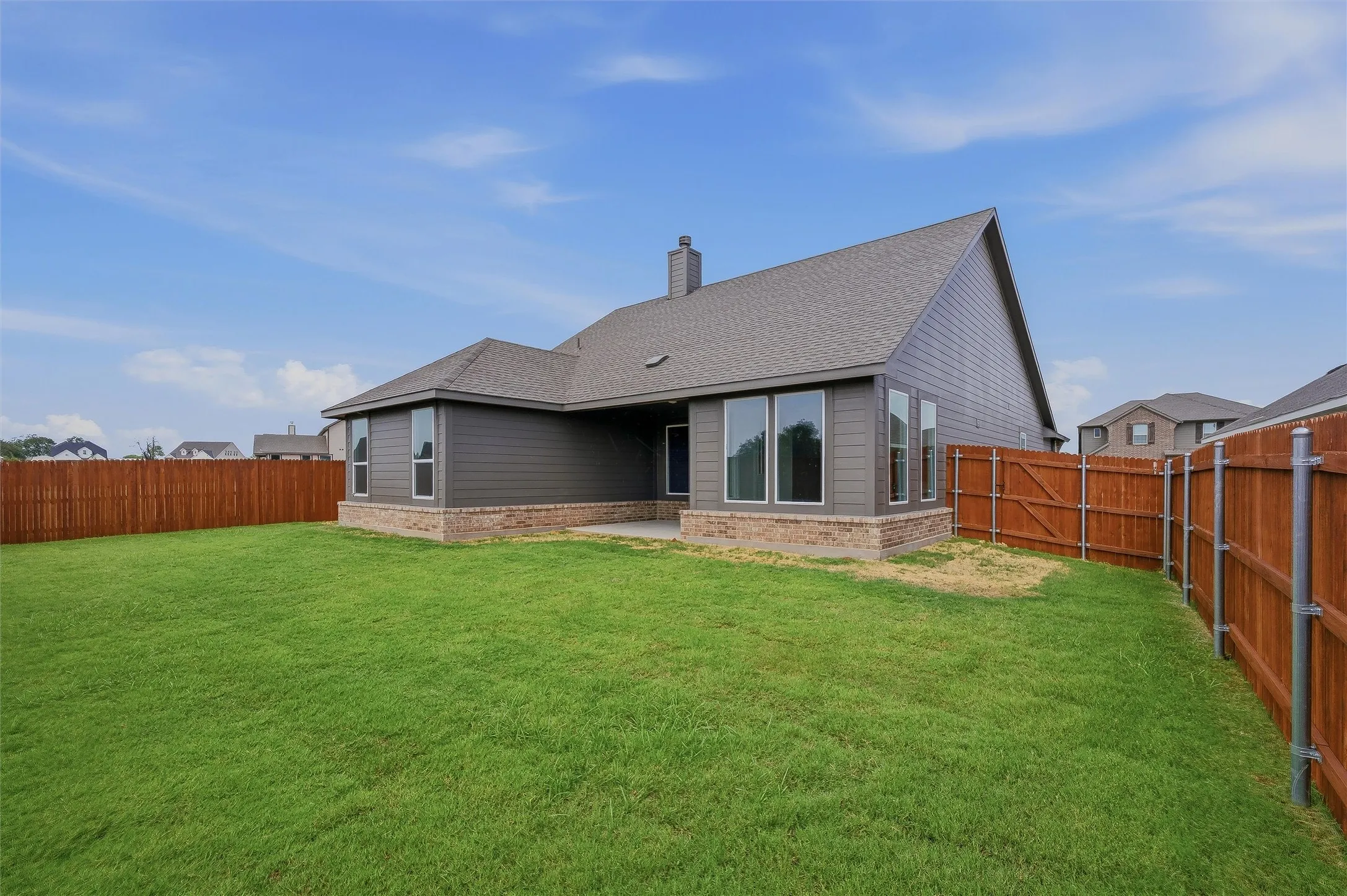 Expansive backyard with a manicured lawn, full wood privacy fencing, and a concrete patio