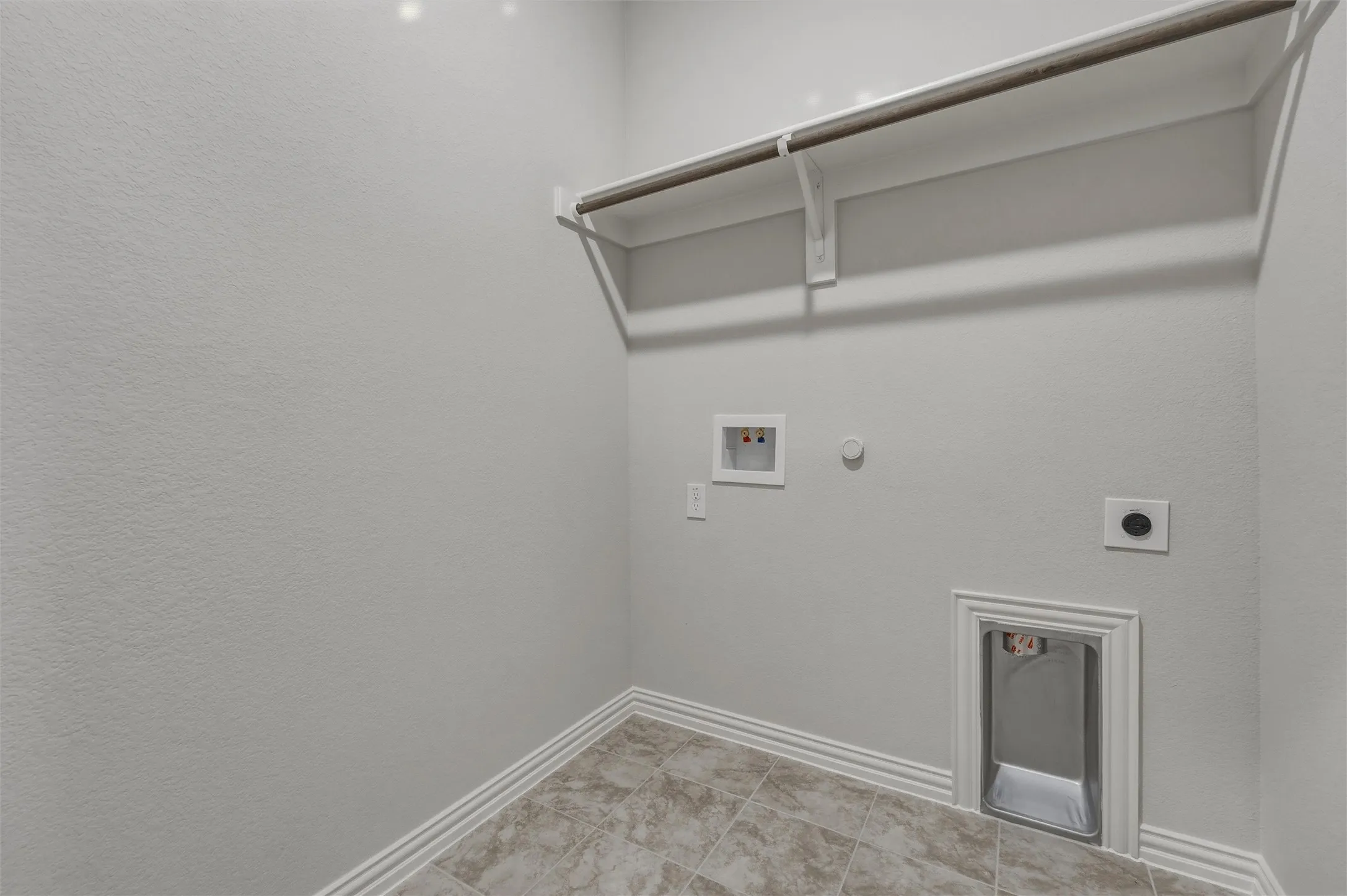 Utility room featuring a built-in shelf, hanging rod, water hookups, and a dryer vent