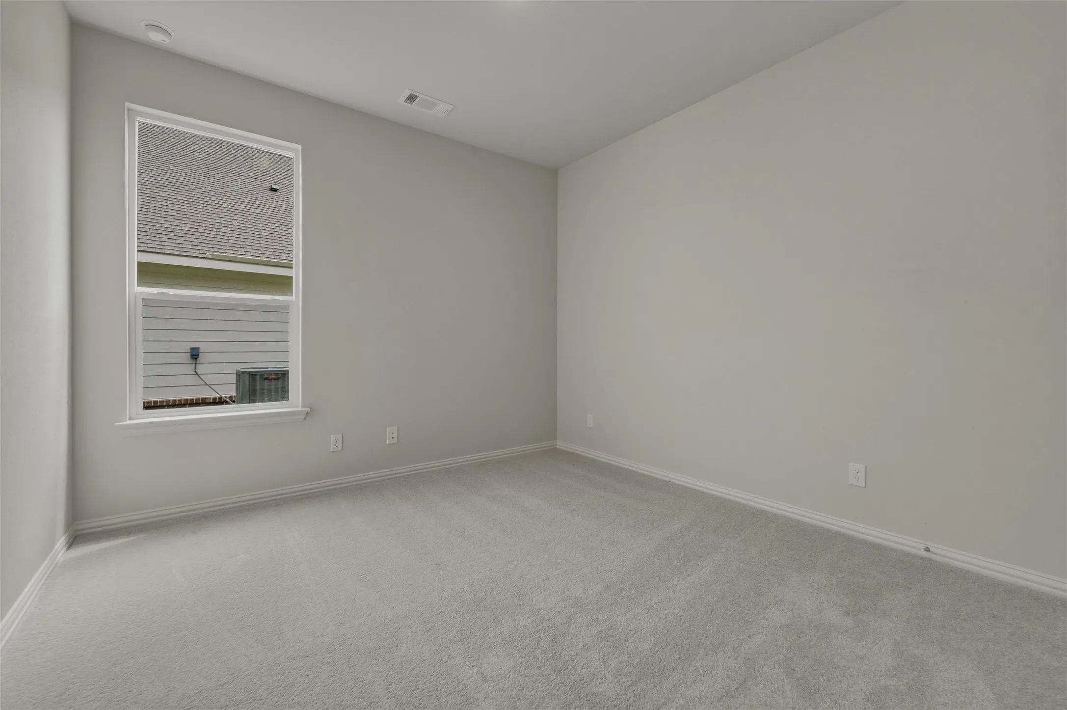 Neutral tone wall paint, light-colored carpeting, white trim, and a double-pane window