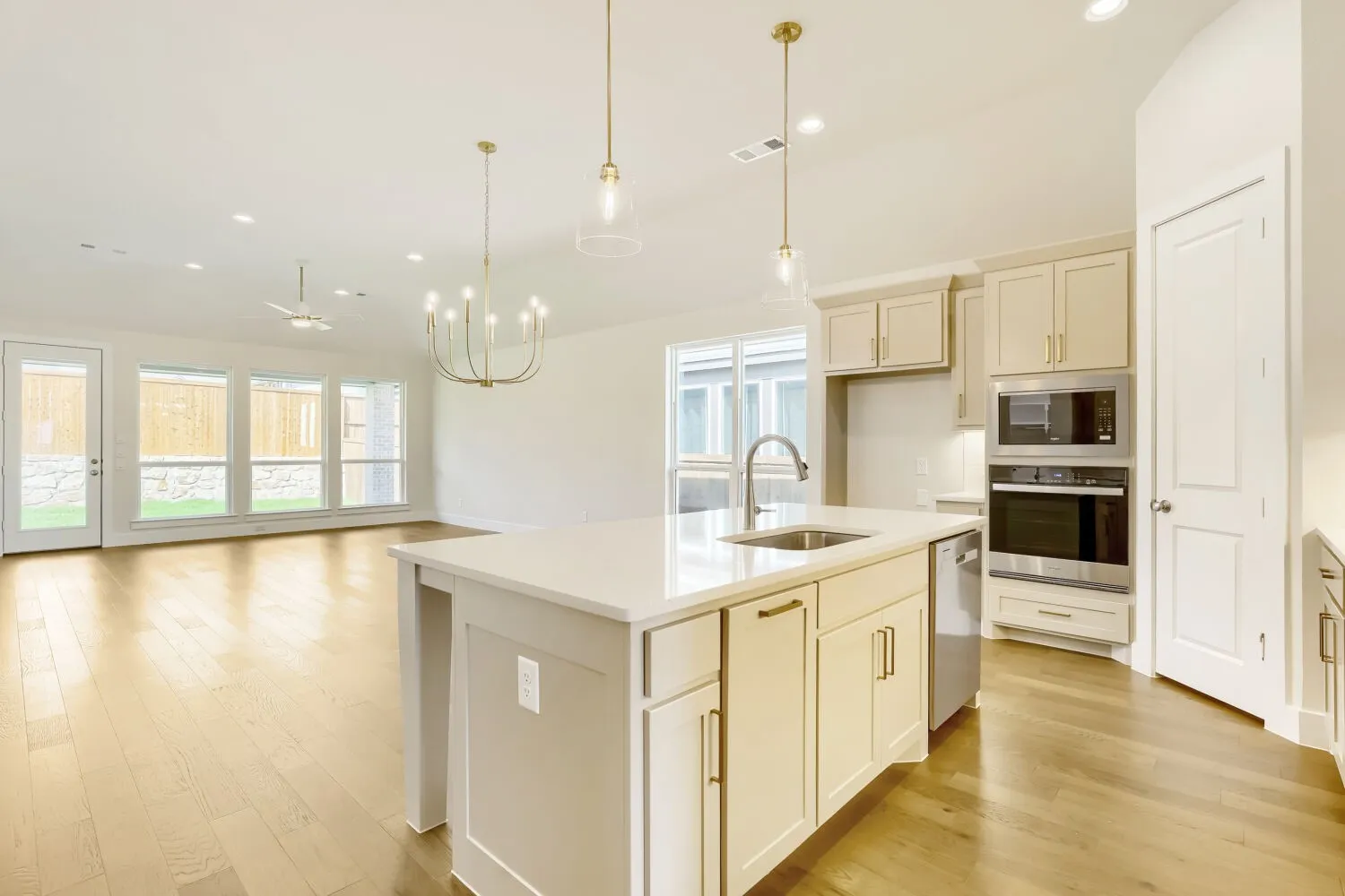 Kitchen island with an undermount sink, stainless steel appliances, and wood-finish flooring