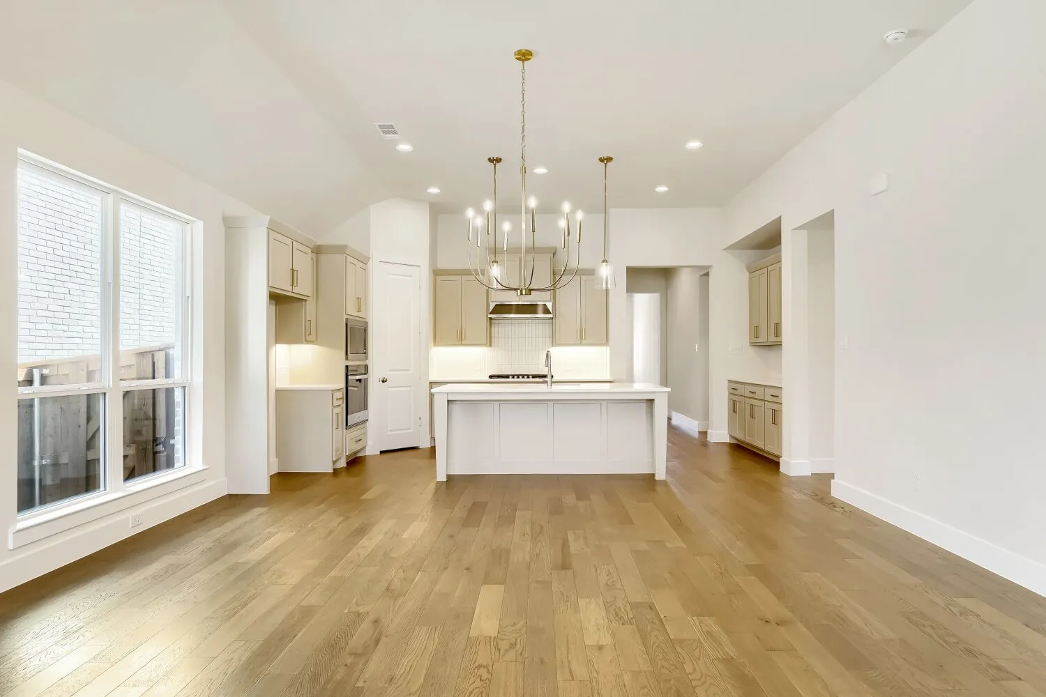 Open-concept living area with wood-finish flooring, a kitchen island, recessed lighting, and a chandelier