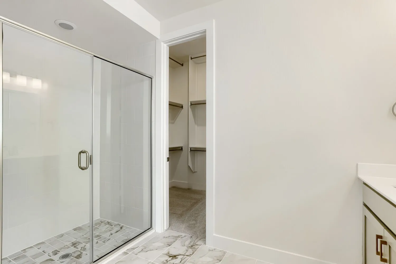 Glass-enclosed shower with subway tile surround and mosaic tile flooring