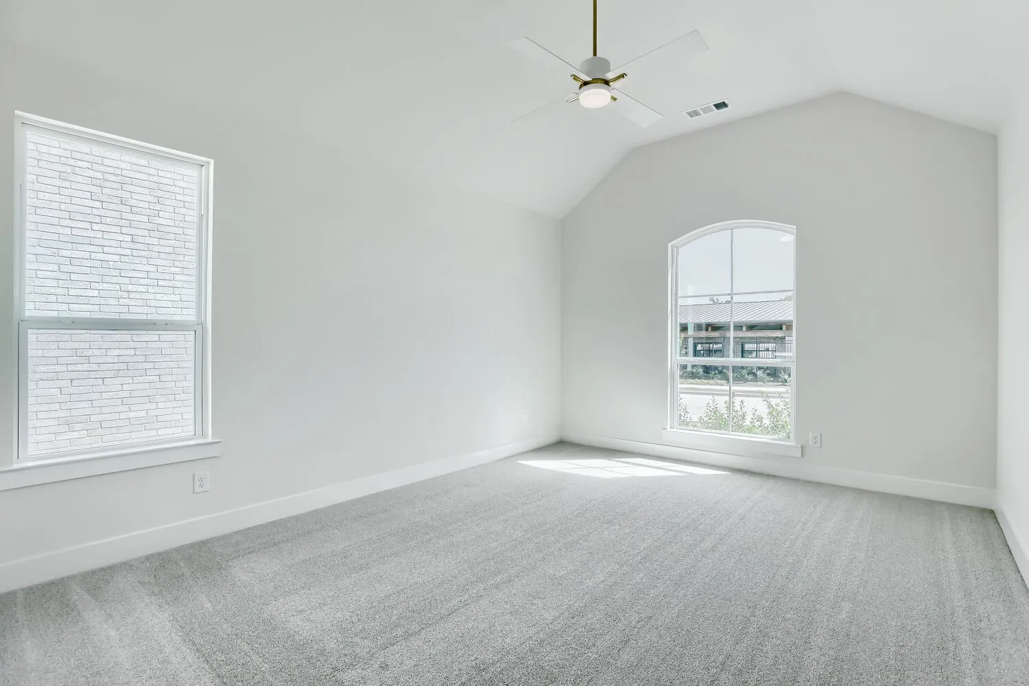 Vaulted ceiling with a ceiling fan, arched window, and plush carpeting