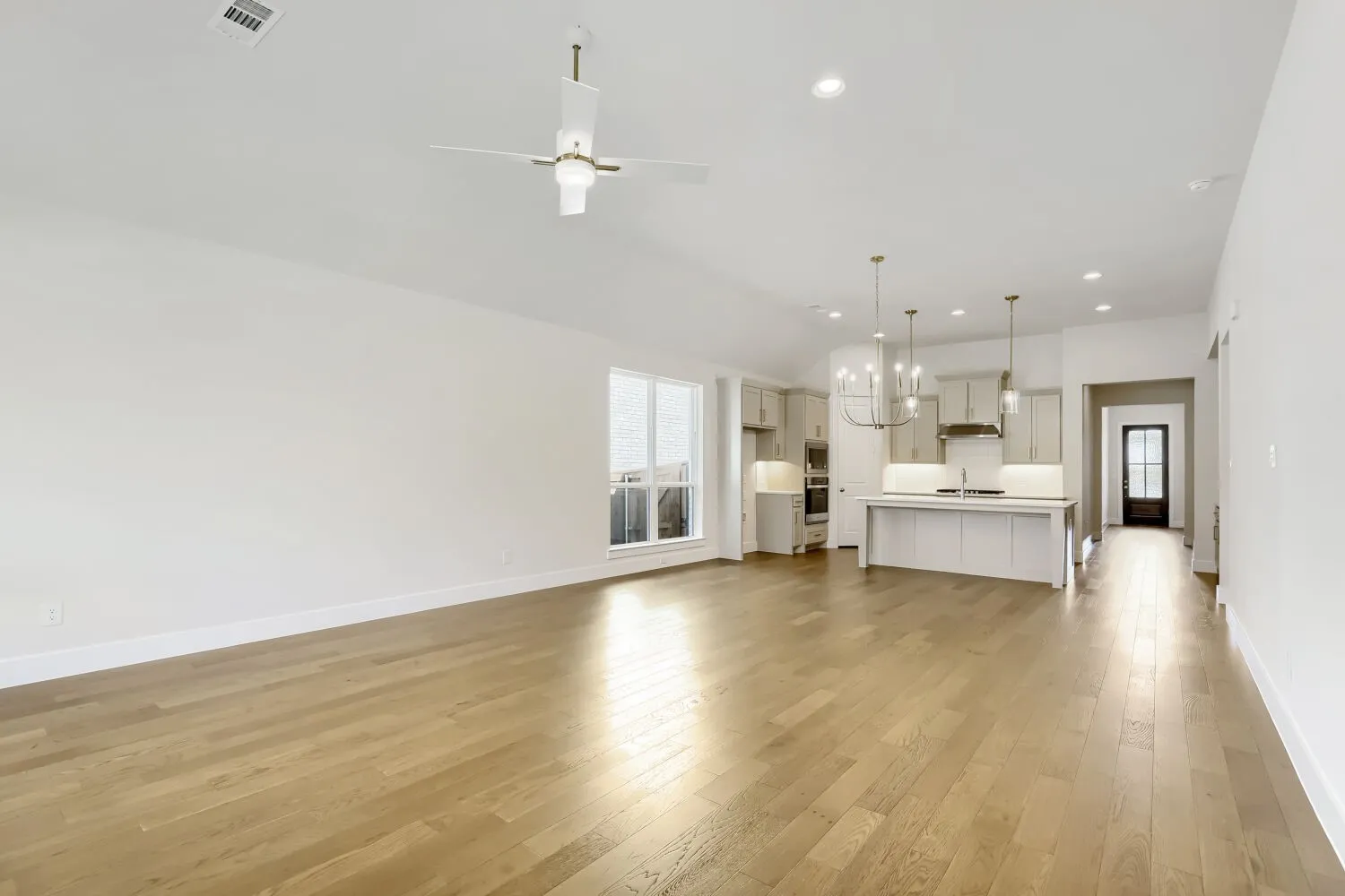 Open concept living space with wood-finish flooring, vaulted ceiling, and recessed lighting