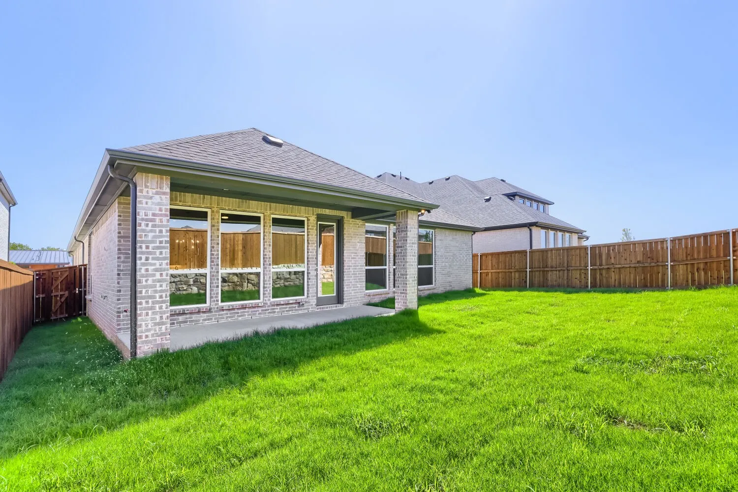 Expansive backyard with a covered patio, full brick exterior, and privacy fencing