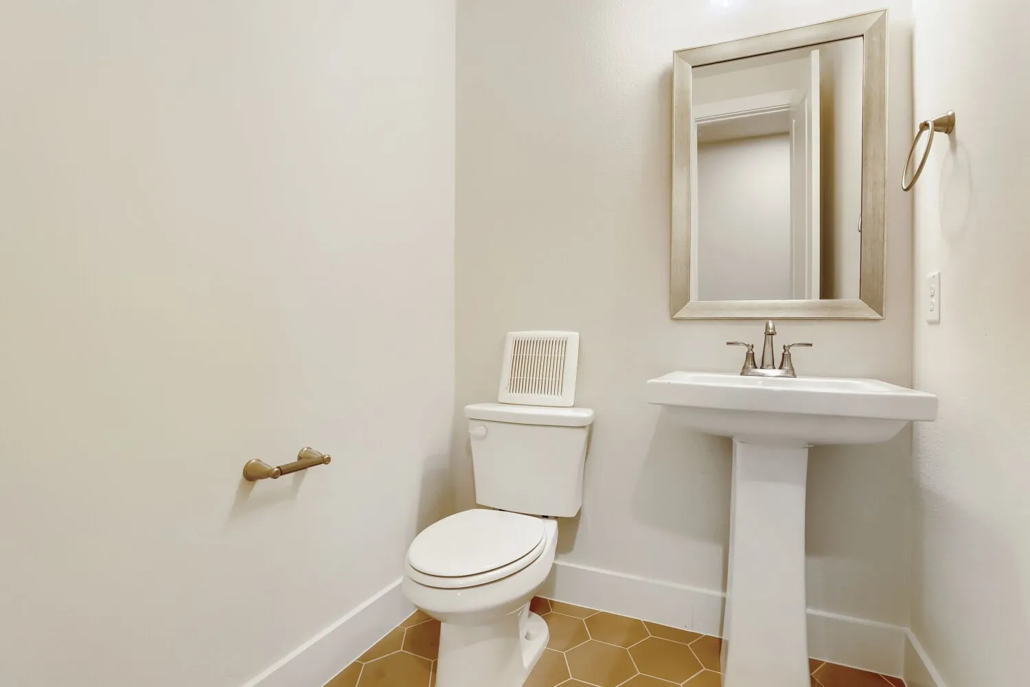 Elegant half bath featuring a pedestal sink with chrome faucet, white porcelain toilet with closed lid, framed medicine cabinet mirror, and warm wood-finish flooring
