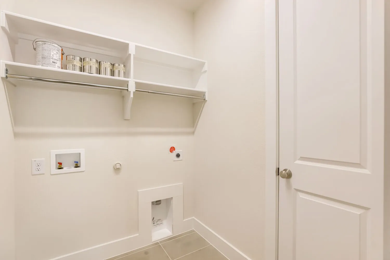 Built-in shelving with hanging rod, utility hookups, and tiled flooring