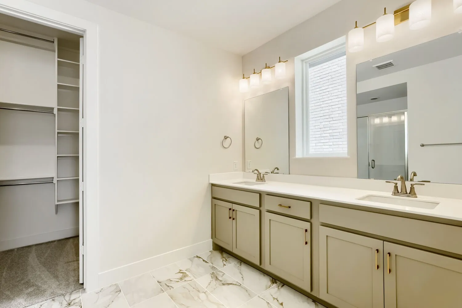 Dual vanity with light countertops, undermount sinks, and gold-finish hardware