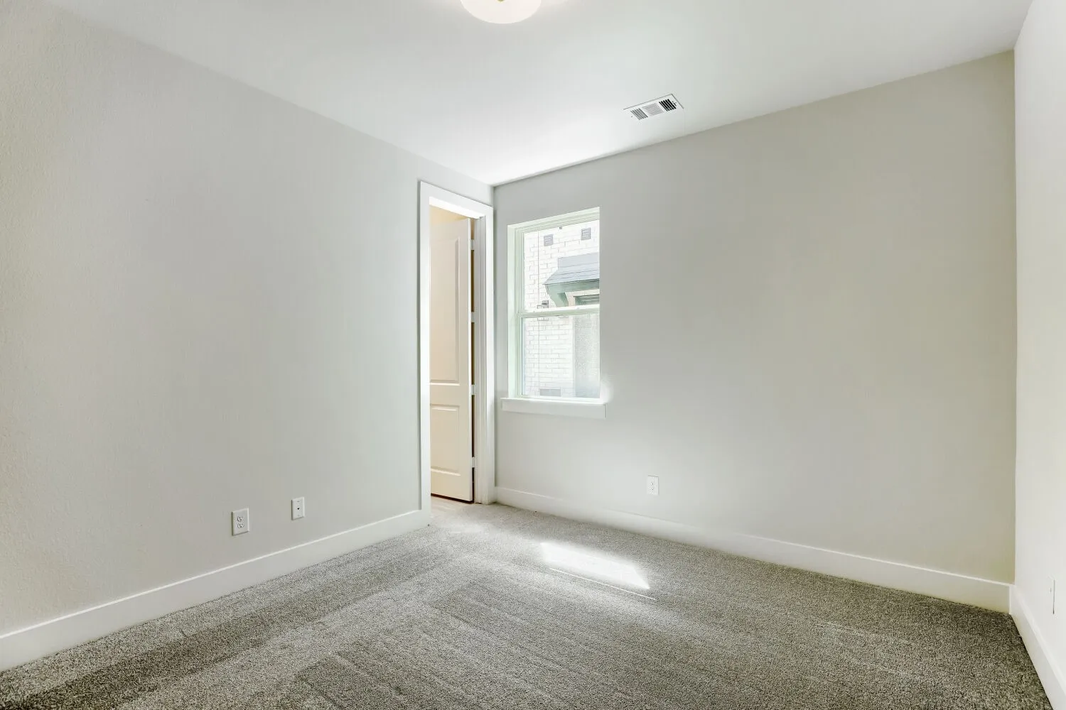 Neutral wall color, carpeted flooring, and a single window