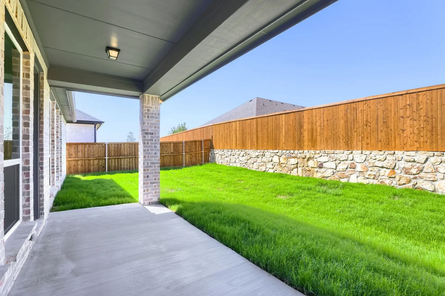 Covered patio with concrete flooring, brick column, and recessed lighting