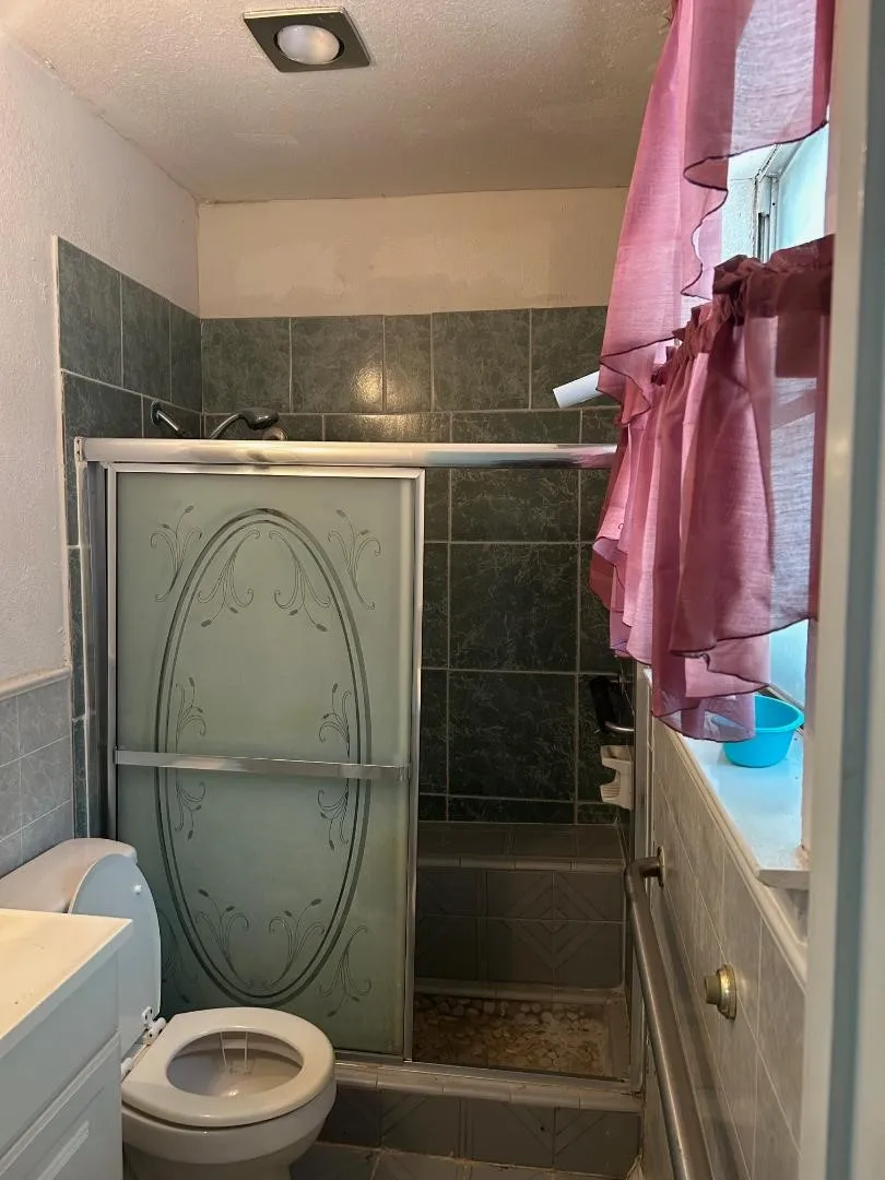 Tiled shower enclosure with frosted glass sliding doors and a built-in bench