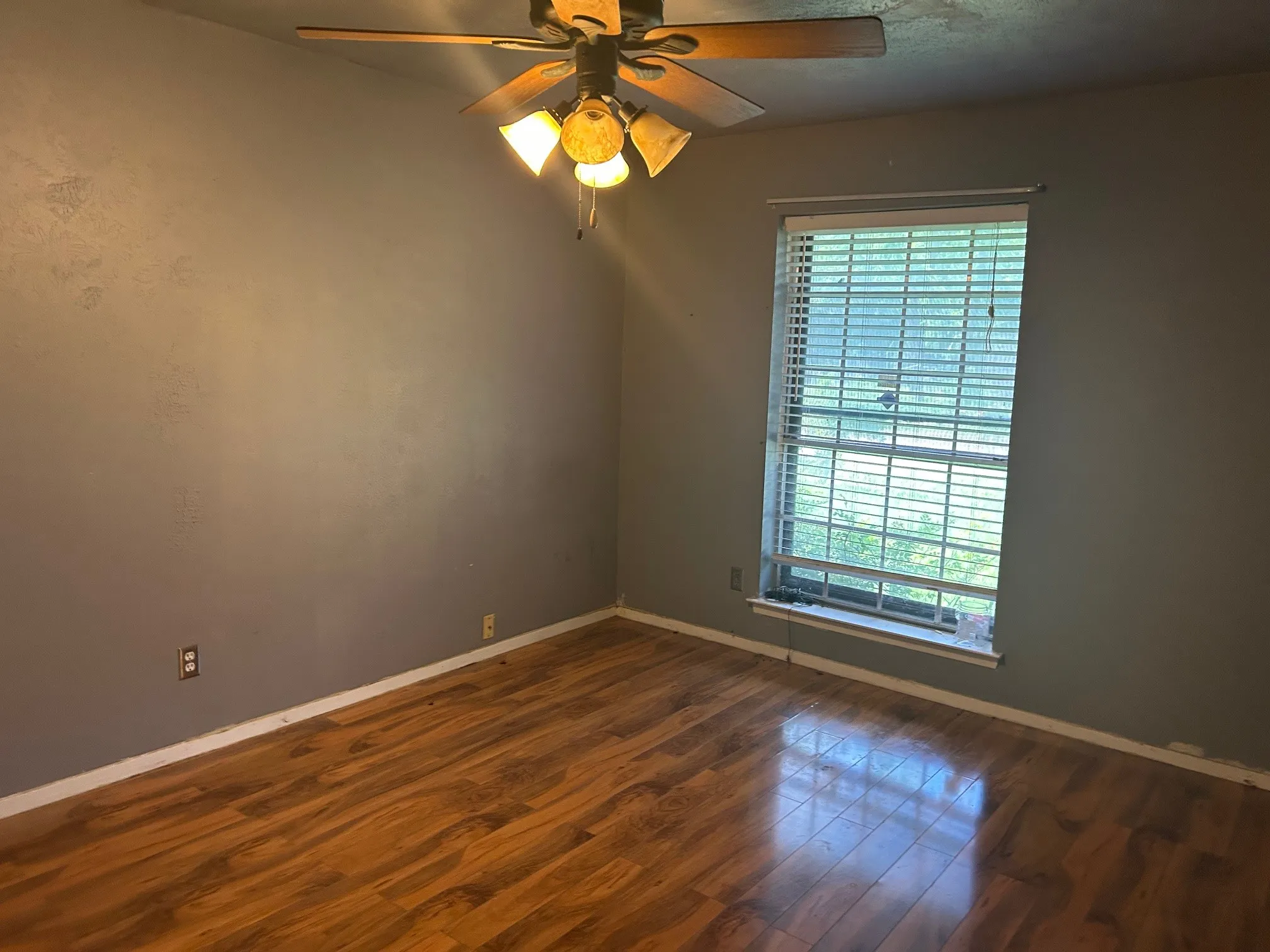 Room #2 featuring wood-finish flooring, a window with horizontal blinds, and a ceiling fan with integrated lighting
