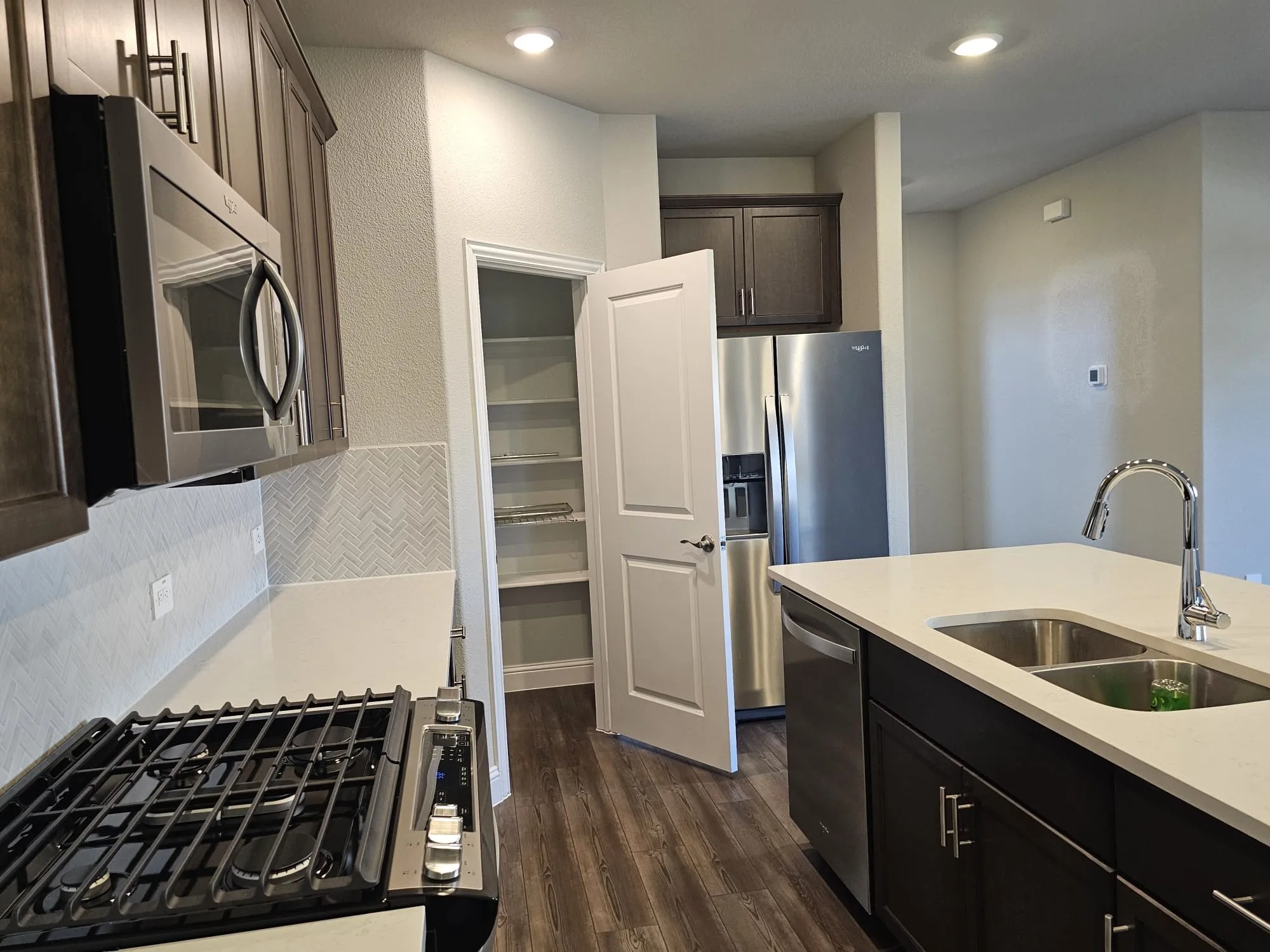 Kitchen with tasteful backsplash, stainless steel appliances, dark brown cabinetry, dark hardwood / wood-style flooring, and sink
