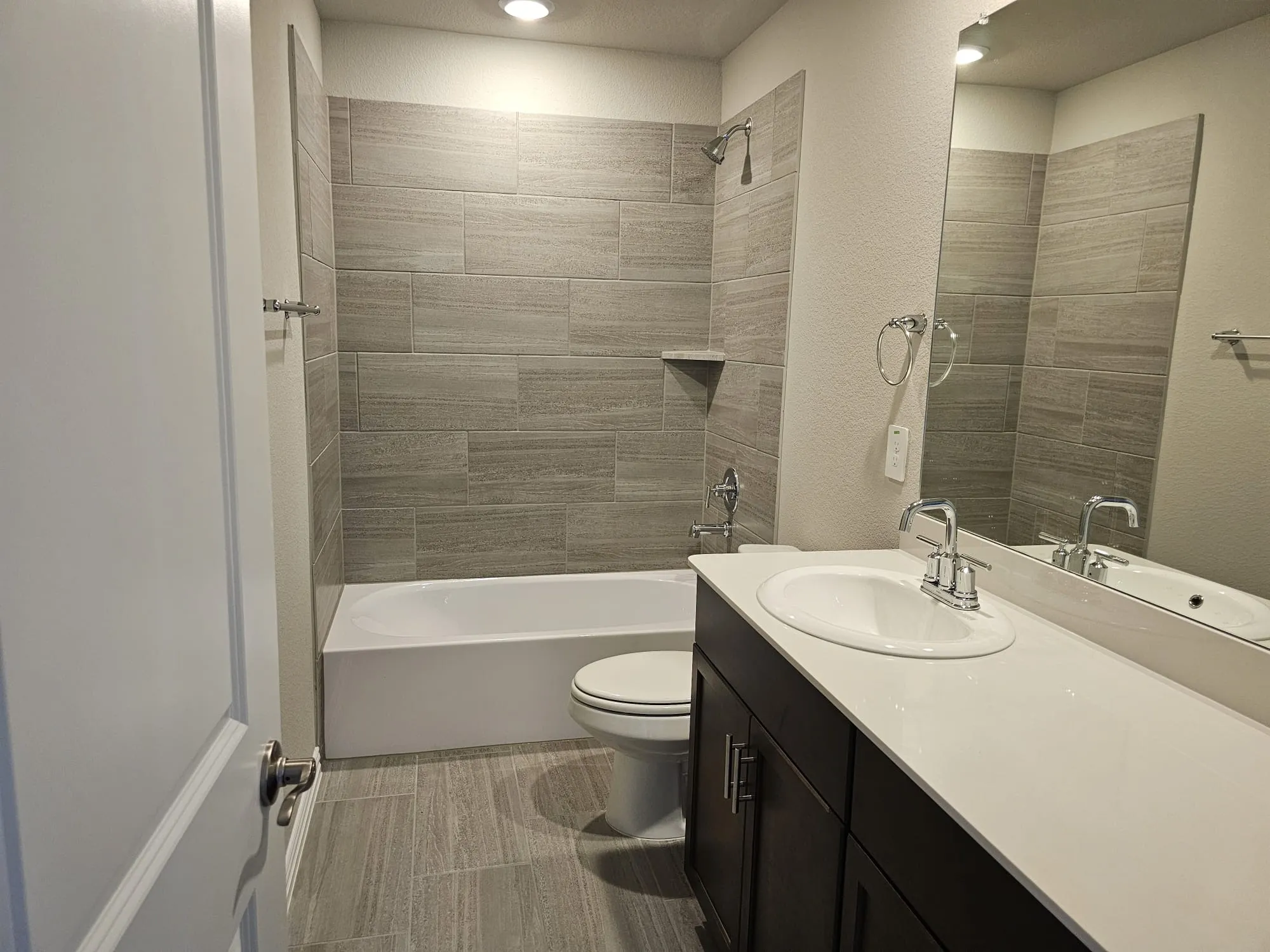 Full bathroom with tiled shower / bath combo, tile flooring, toilet, and vanity