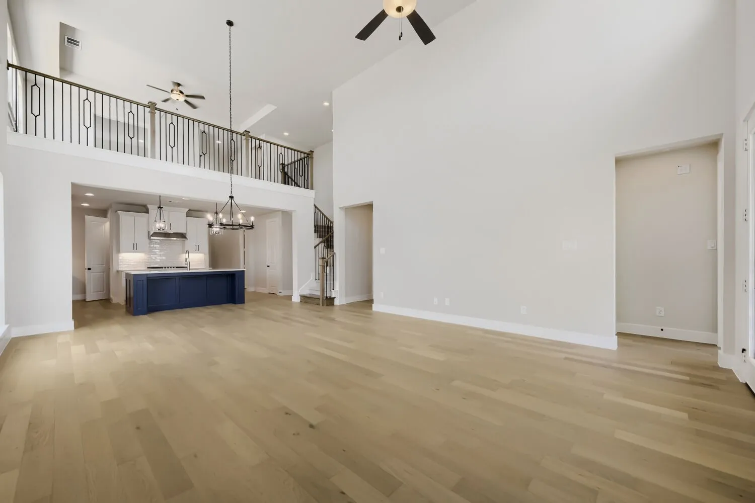 Soaring two-story great room with high ceilings, pendant lighting, and wide-plank wood-finish flooring