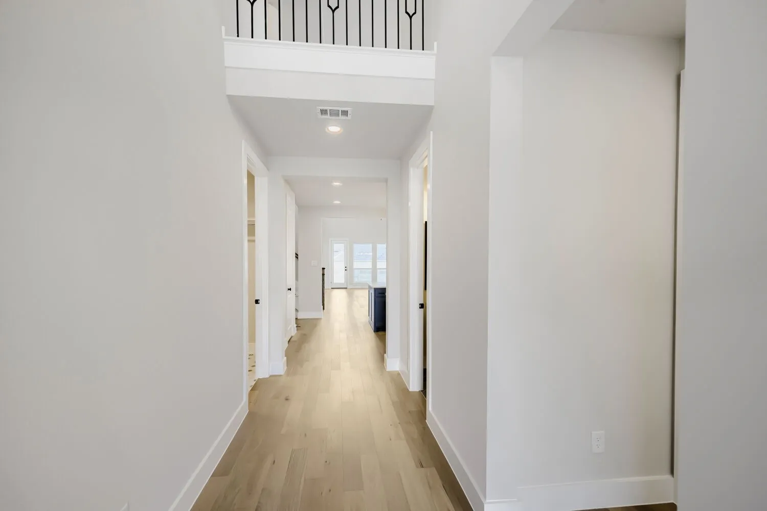 Bright hallway showcasing gleaming wood-finish flooring, clean white walls, and recessed ceiling lighting