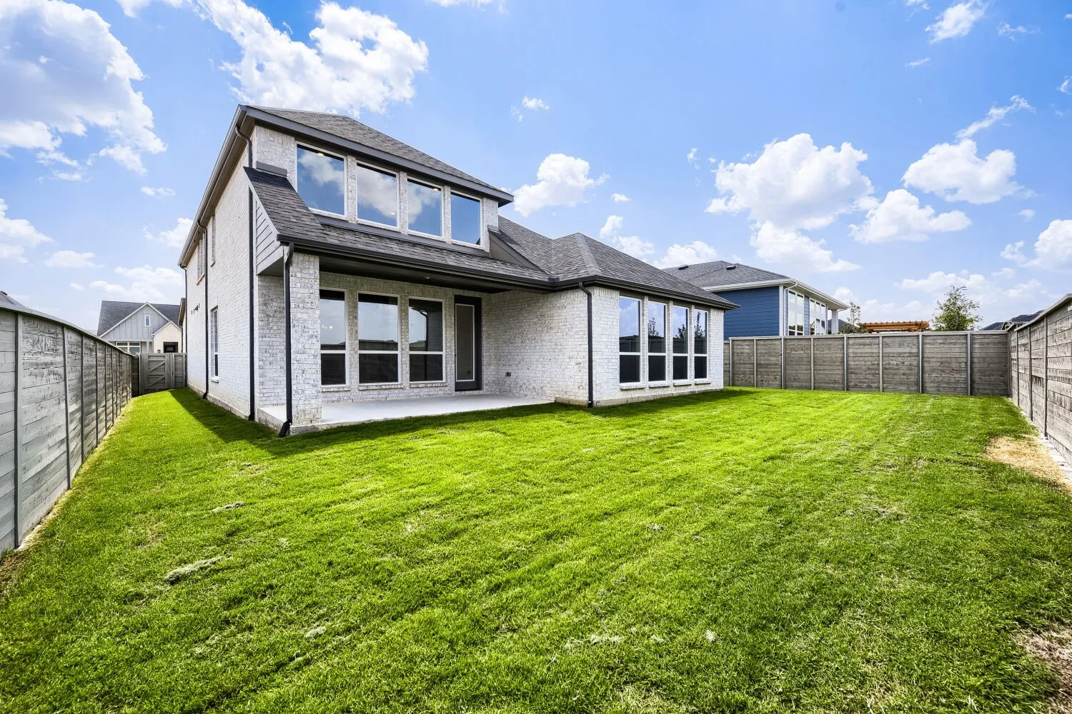 Expansive backyard with a manicured lawn, a concrete patio, and a privacy fence