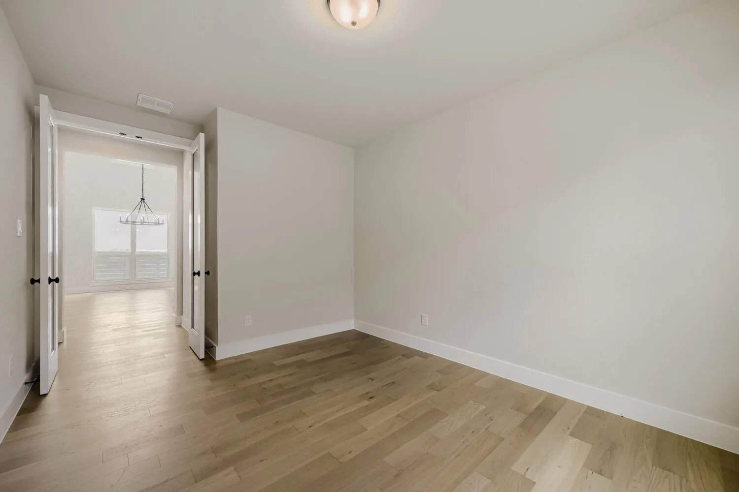 French doors with matte black hardware, wood-finish flooring, recessed lighting, and white baseboards