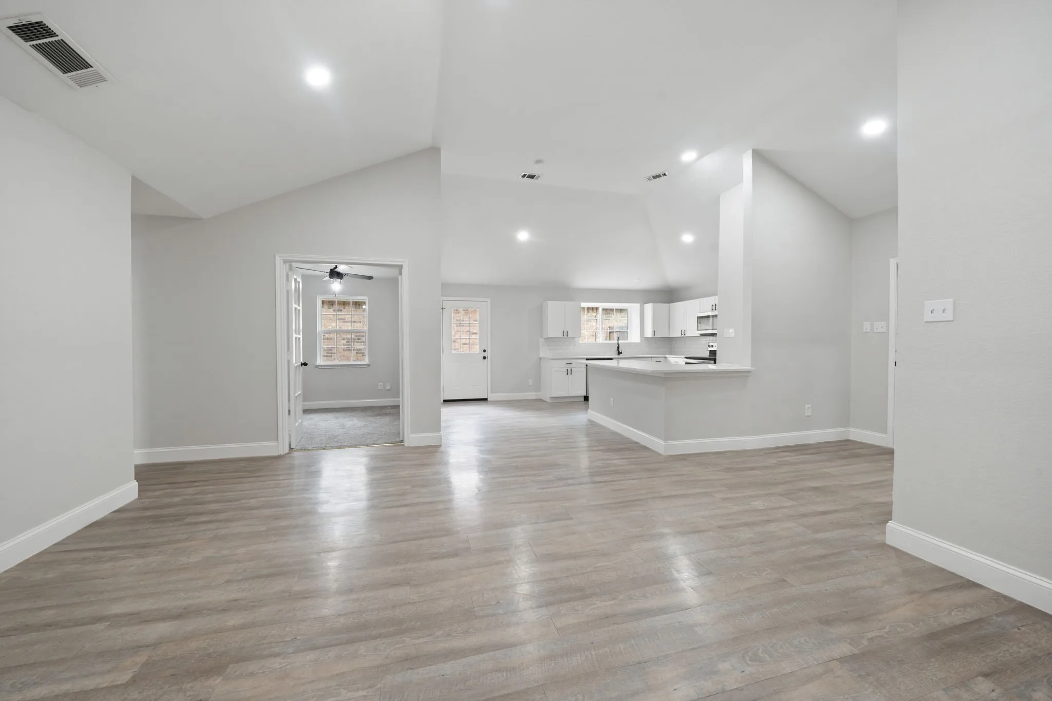 Spacious room featuring wood-finish flooring, vaulted ceilings, and recessed lighting