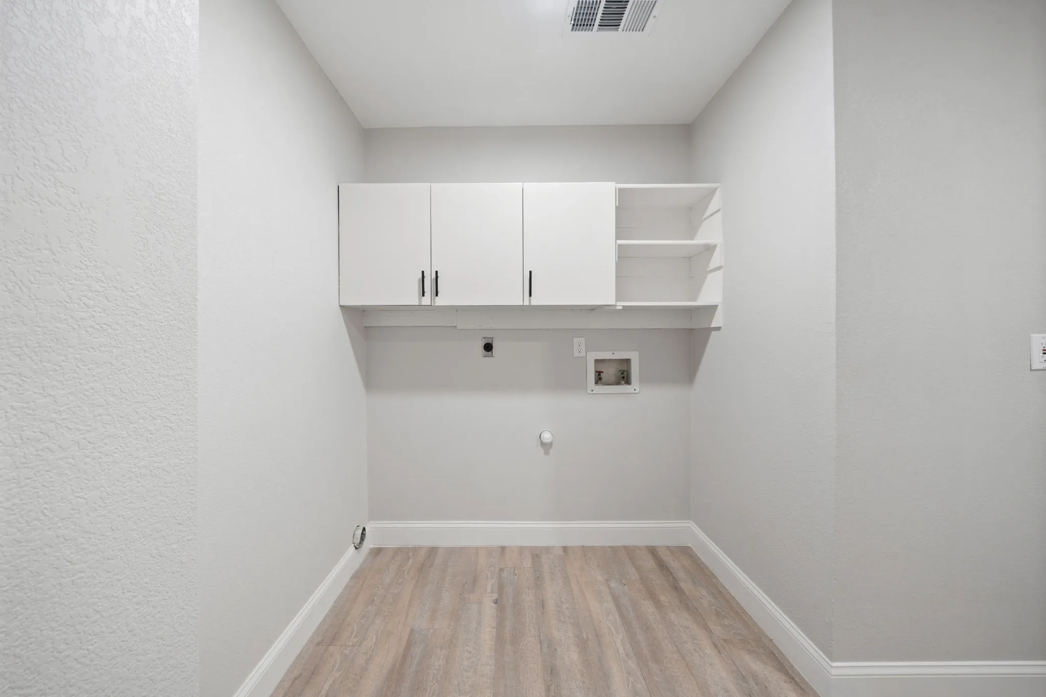 Dedicated utility space featuring light wood-finish flooring, white baseboards, and neutral wall tones
