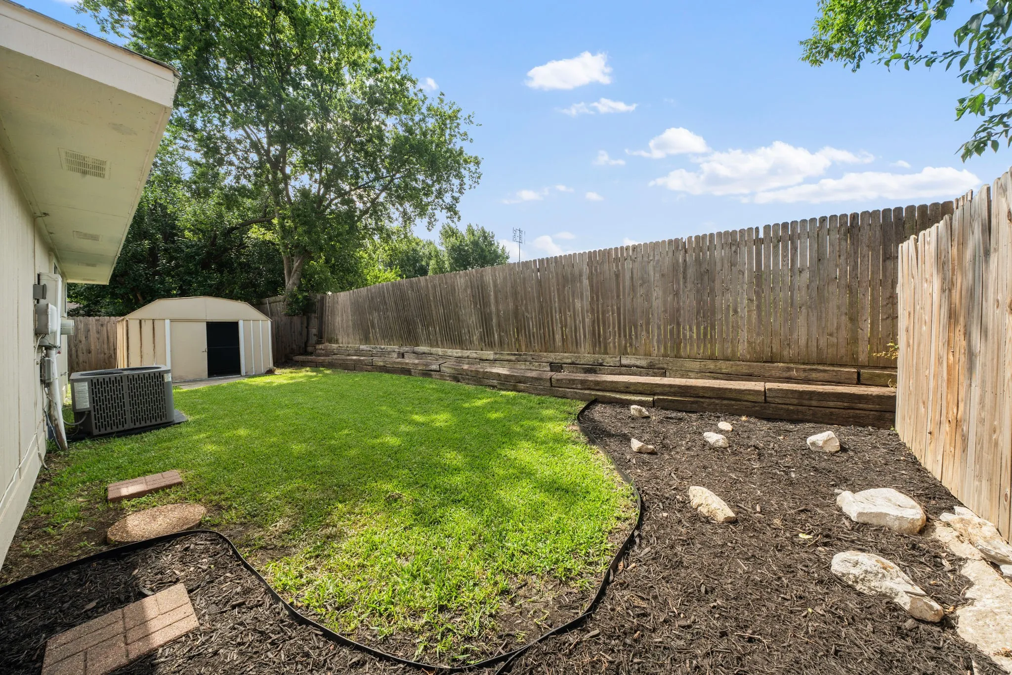 Backyard featuring a manicured lawn, full privacy fencing, and a detached storage shed