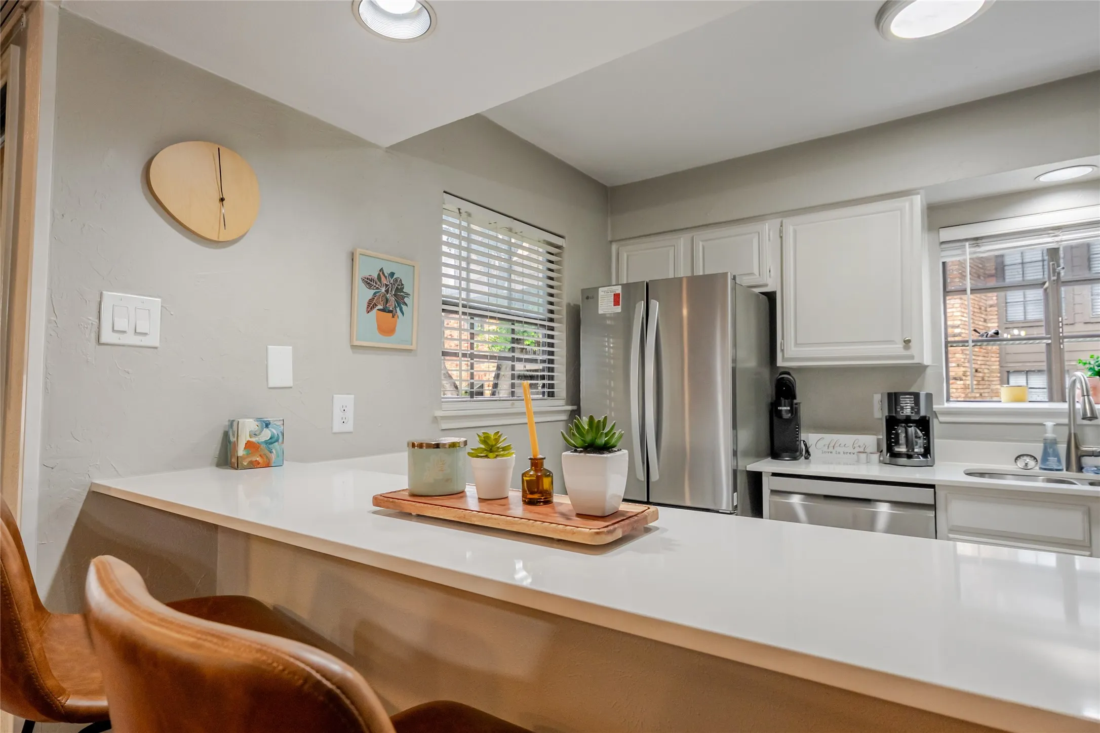 Kitchen featuring a white countertop island, stainless steel appliances, white cabinetry, recessed lighting, and a window with blinds
