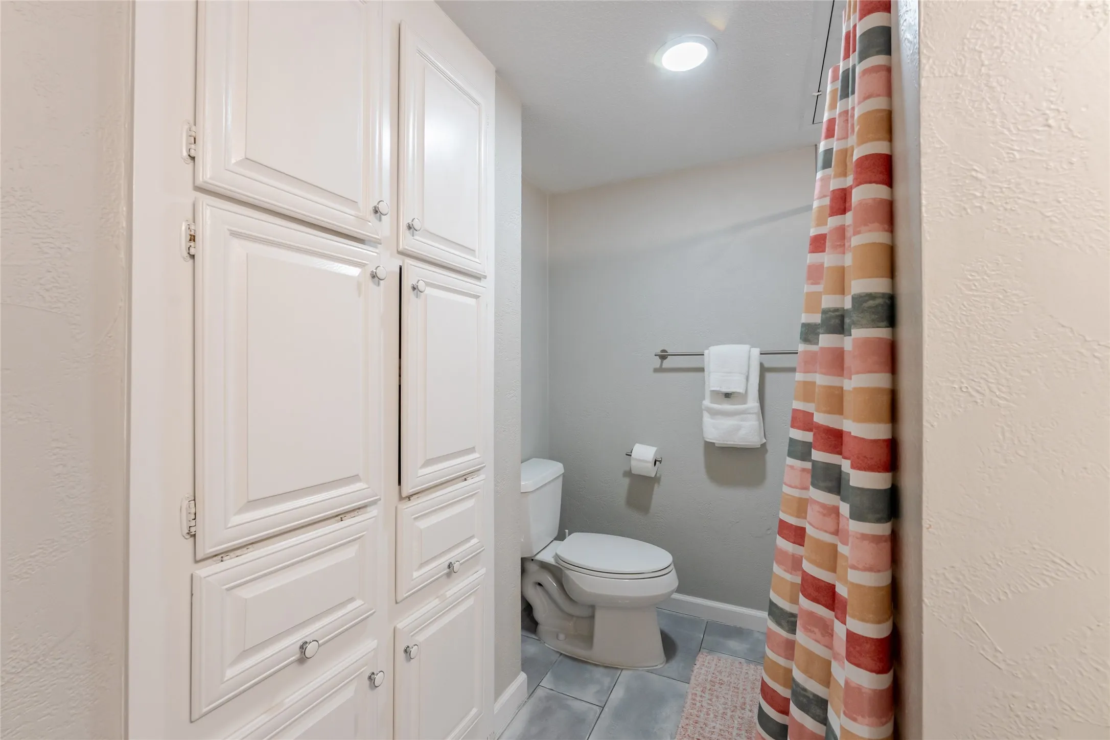 Built-in cabinetry with paneled doors and clear knobs, gray wall paint, recessed lighting, and tile flooring