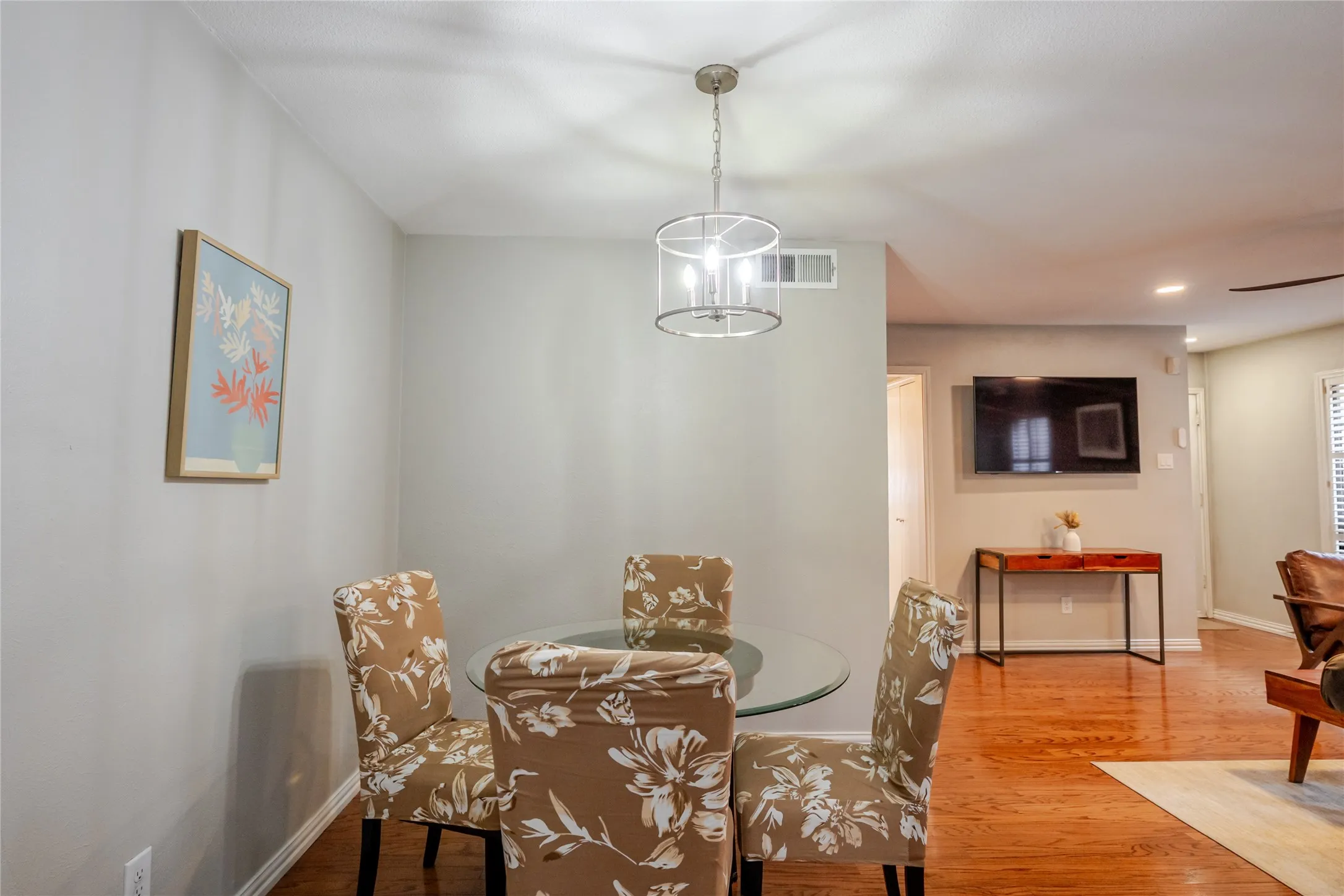 Open concept dining area featuring a contemporary chandelier, hardwood flooring, and light-toned walls