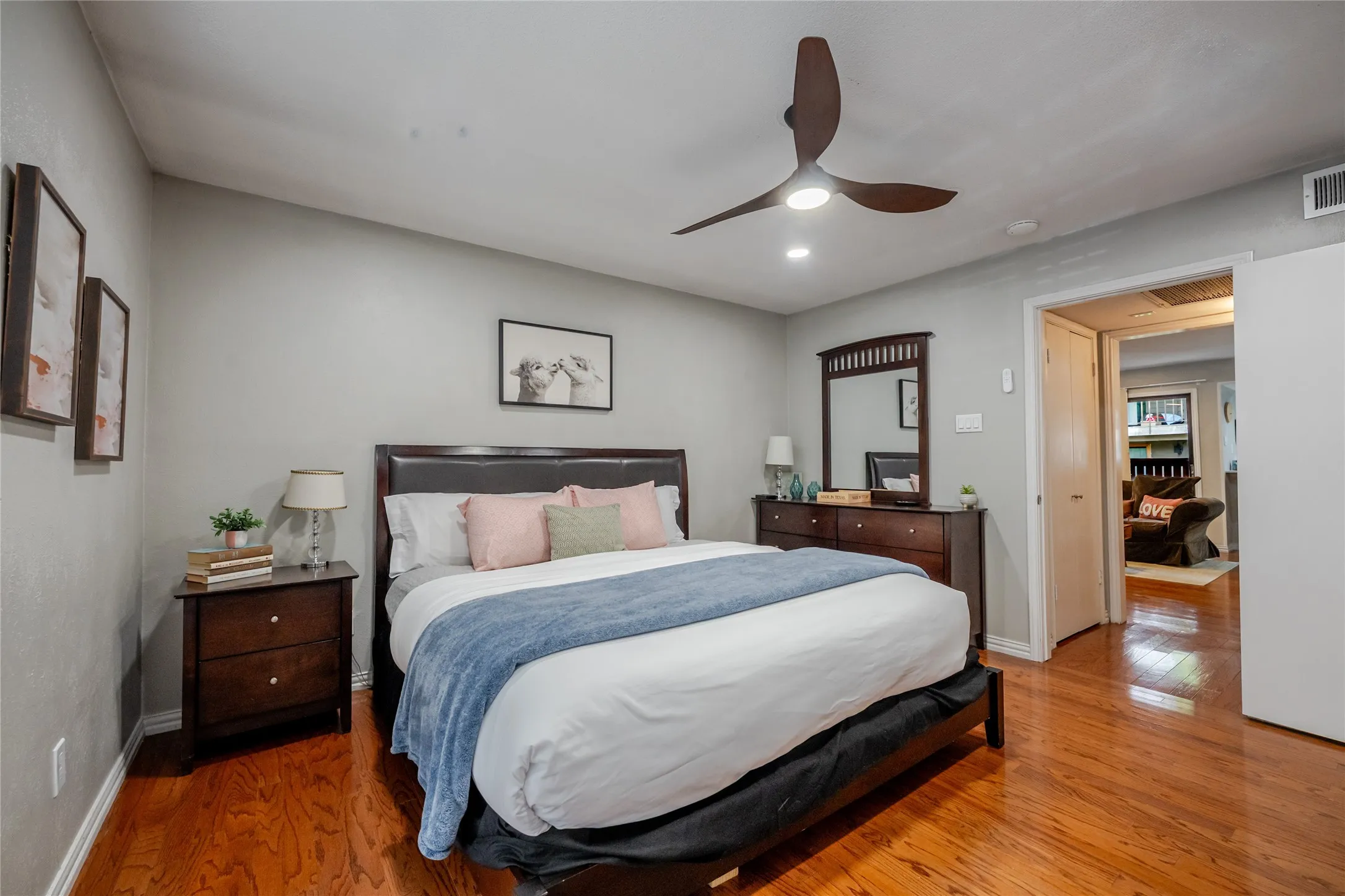 Spacious sleeping area featuring wood-finish flooring, a contemporary ceiling fan with integrated lighting, recessed overhead lighting, and ample wall space