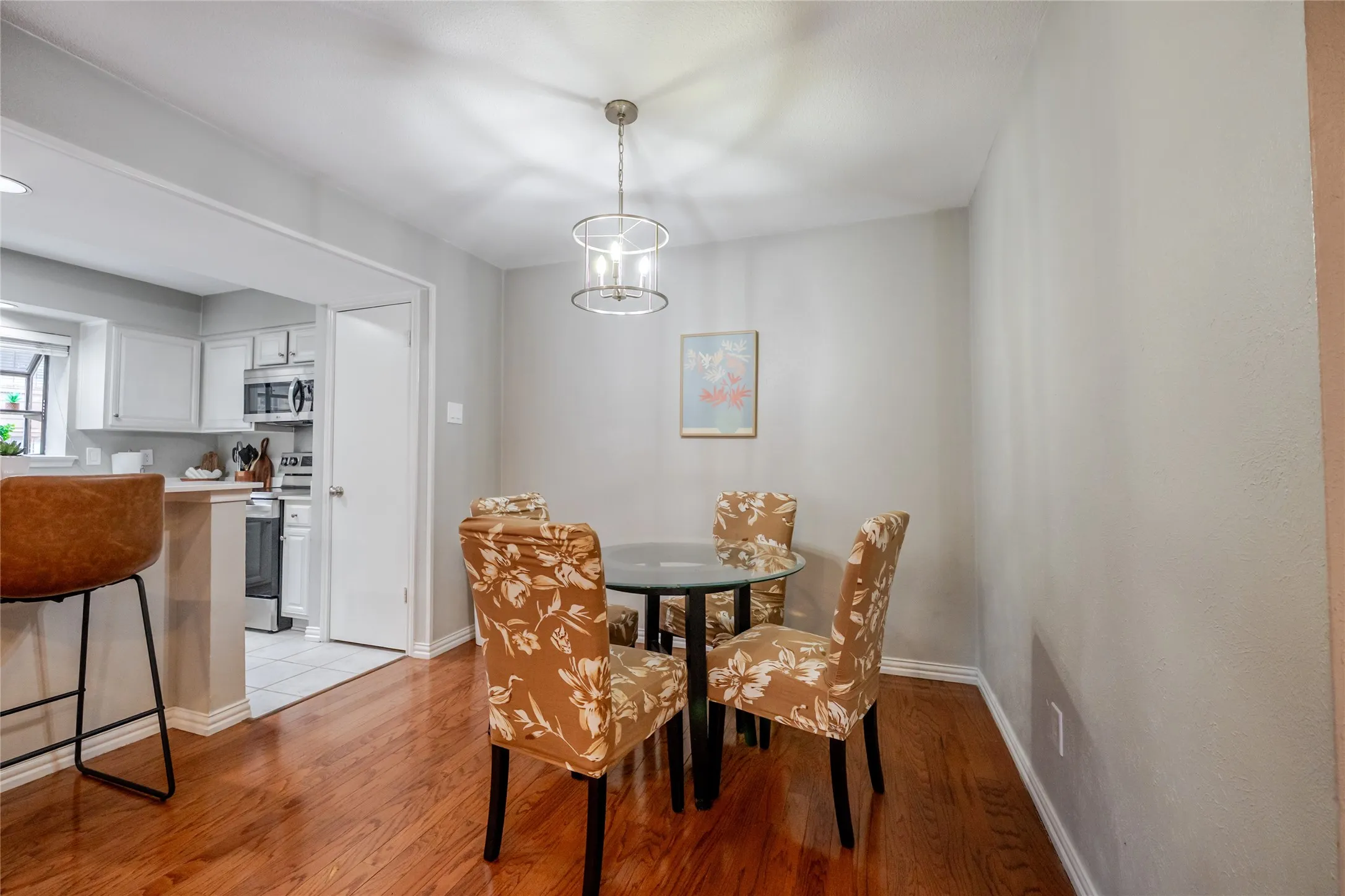 Dining area featuring wood-finish flooring, a contemporary chandelier, and a framed art piece