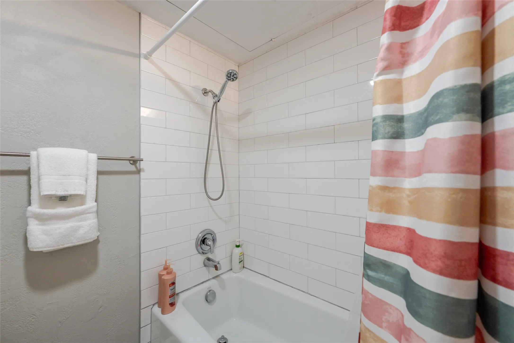 Bathtub and shower combination featuring subway tile surround, chrome fixtures, and a curved shower rod