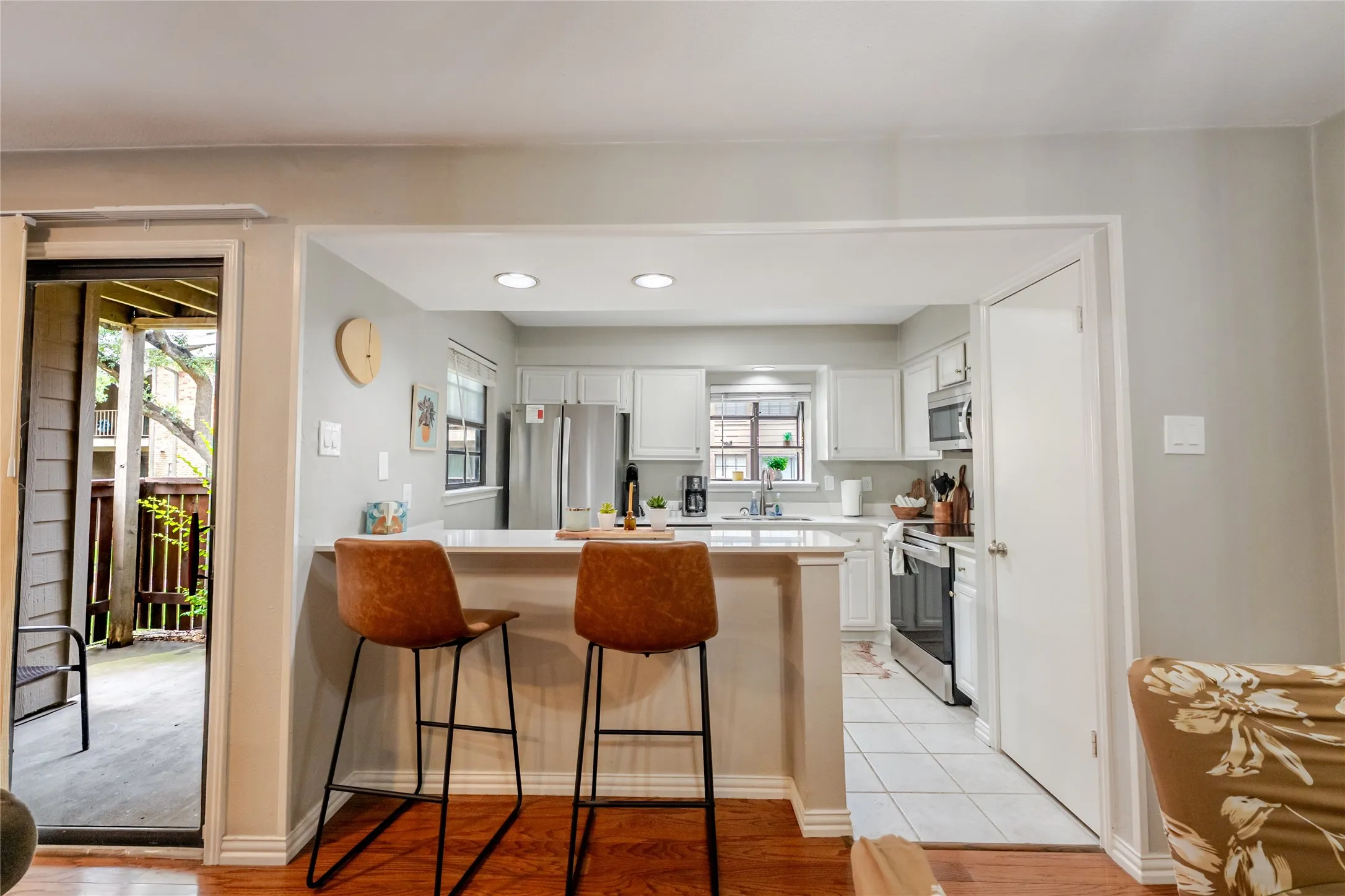 Kitchen featuring white cabinetry, stainless steel appliances, recessed lighting, and a breakfast bar with a light-colored countertop
