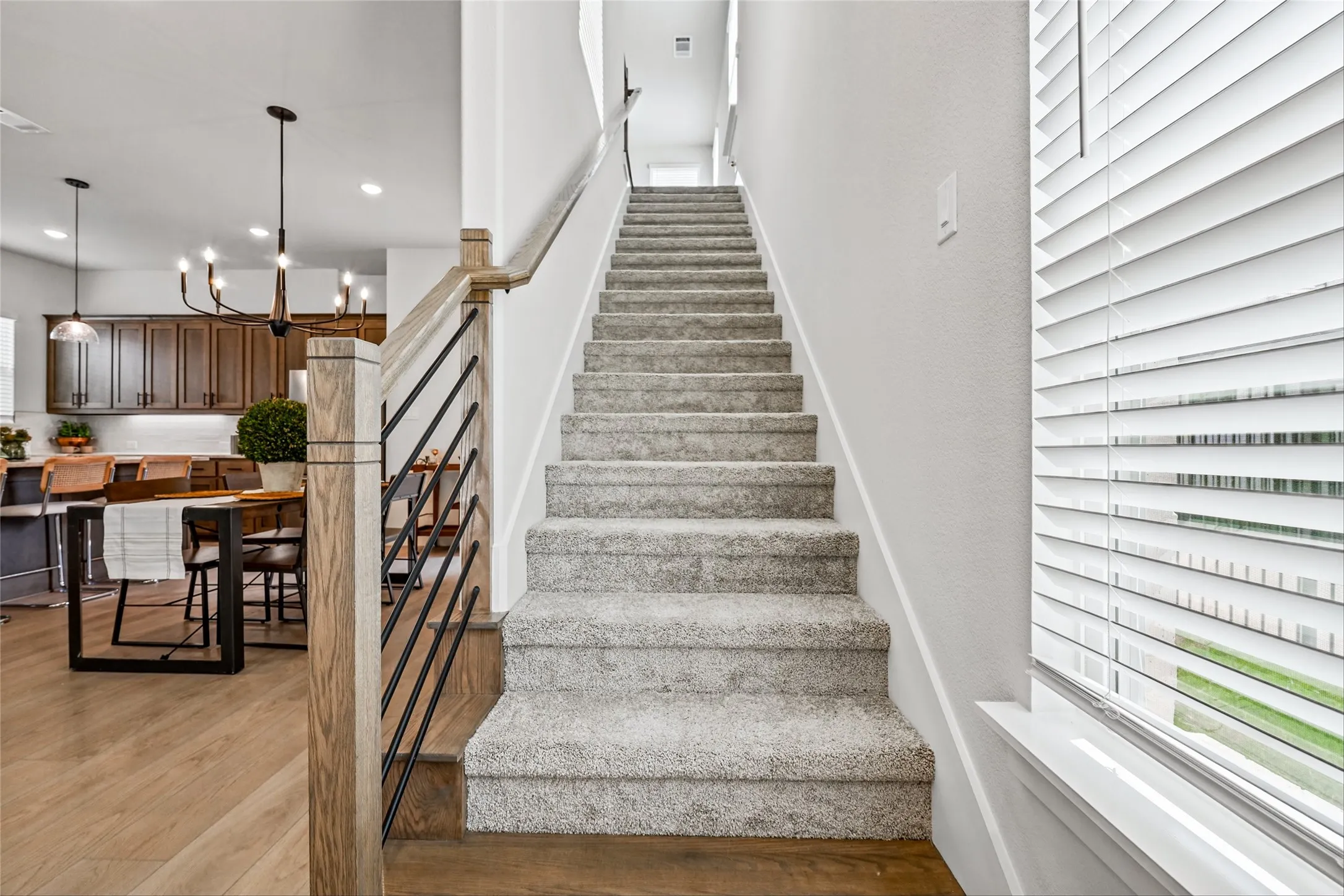 Staircase with carpeted treads and wood-finish railing featuring black metal balusters