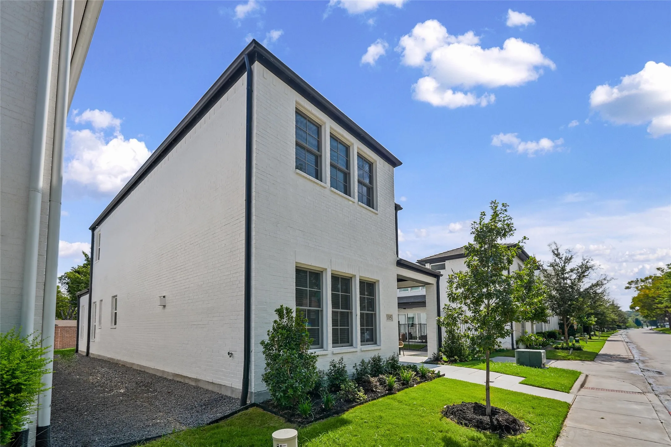 Two-story white brick exterior with dark trim and multiple windows