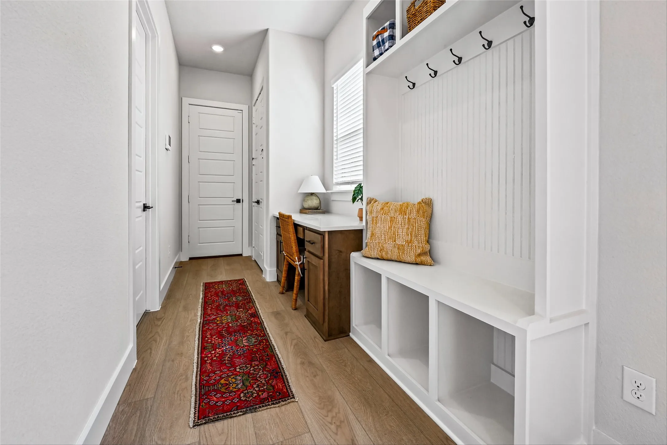 Wood-finish flooring throughout, with a built-in bench featuring storage cubbies, integrated coat hooks, and an upper shelf