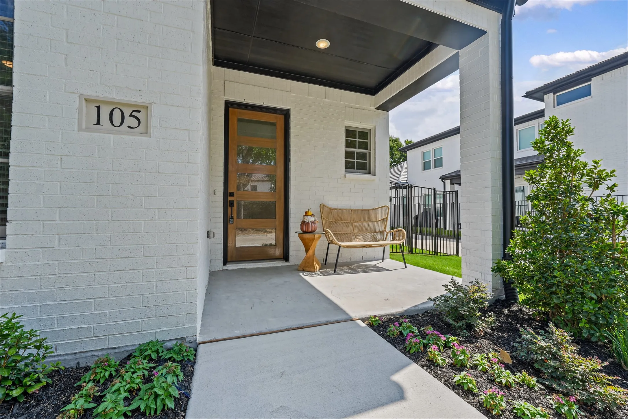 White brick exterior with a black soffit, featuring a wood-finish entry door with four lites