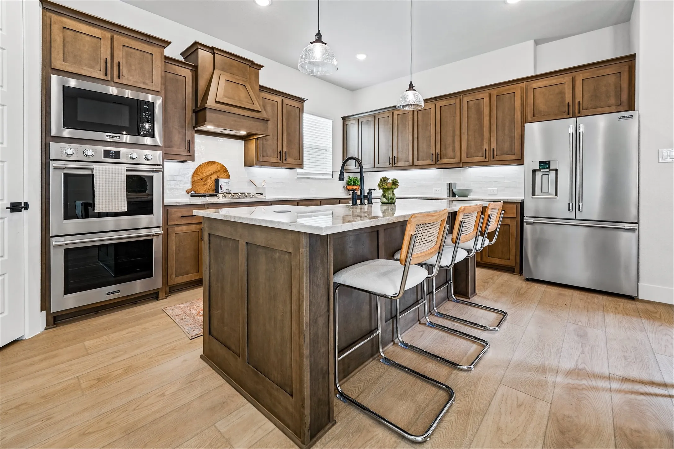 Kitchen featuring wood-finish flooring, recessed lighting, wood cabinetry, stone countertops, and stainless steel appliances