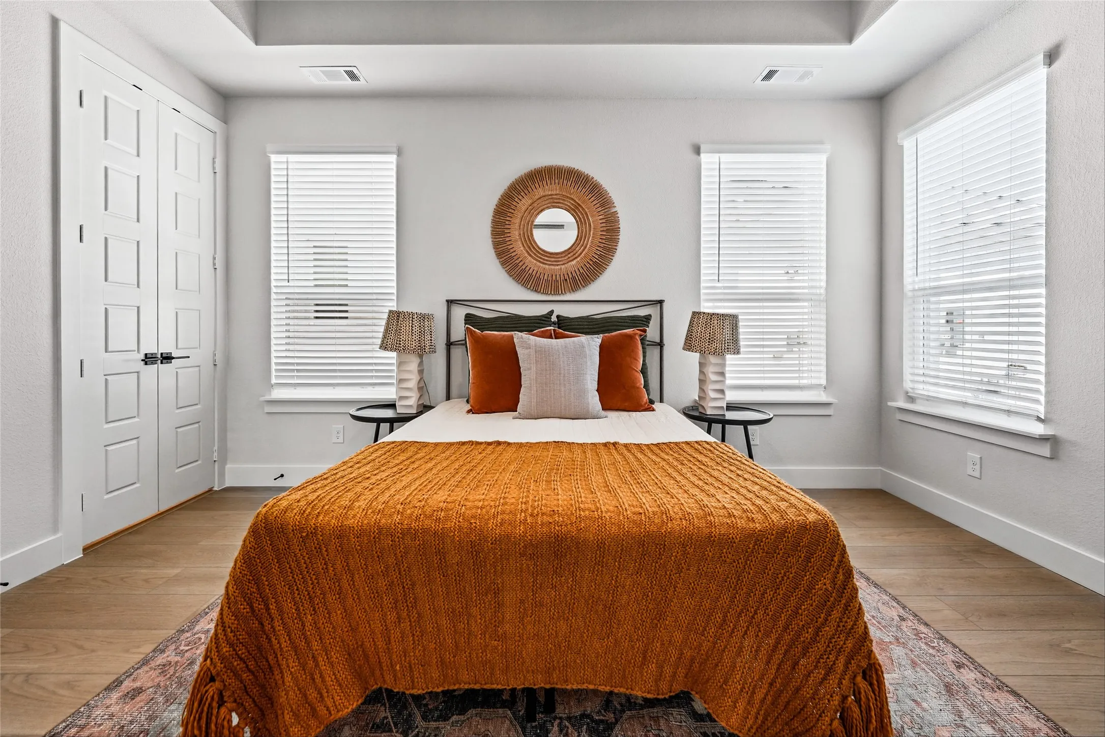 Tray ceiling, wood-finish flooring, white paneled double doors, window treatments, and recessed window casings
