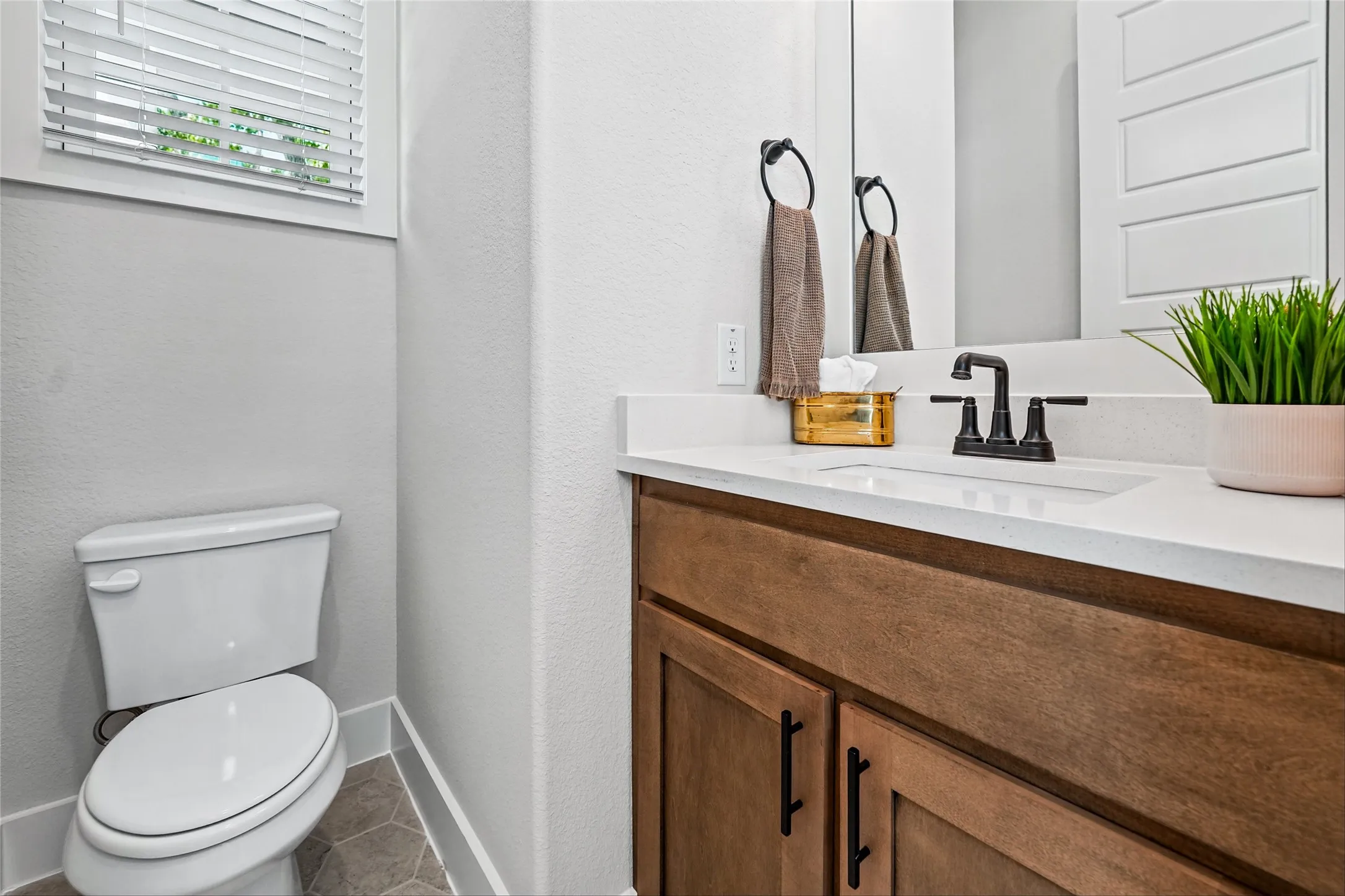 White vanity countertop with an integrated sink, dark wood-finish cabinetry, and a black hardware faucet