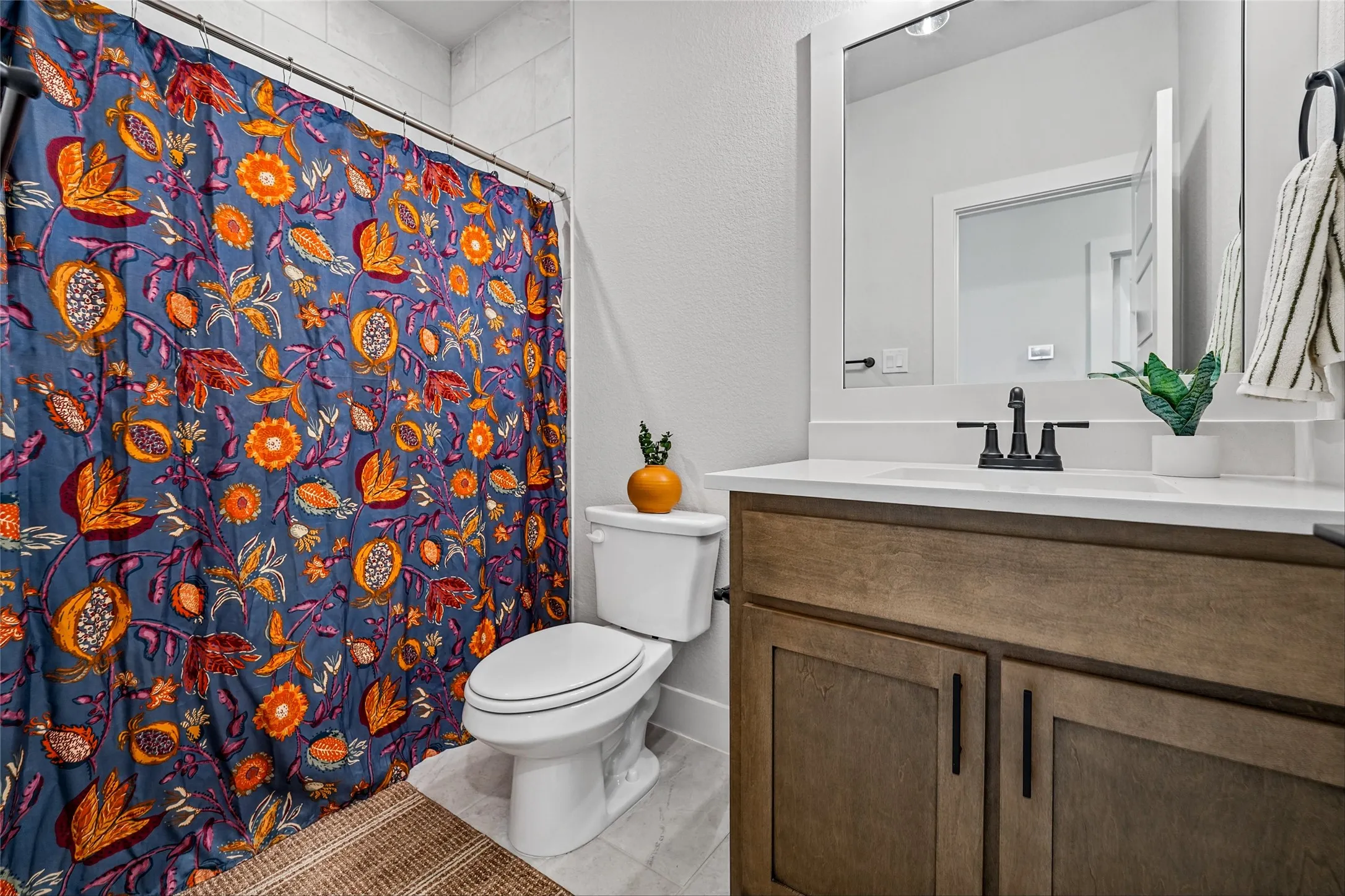 Bathroom featuring wood-finish vanity, white countertop, and framed mirror