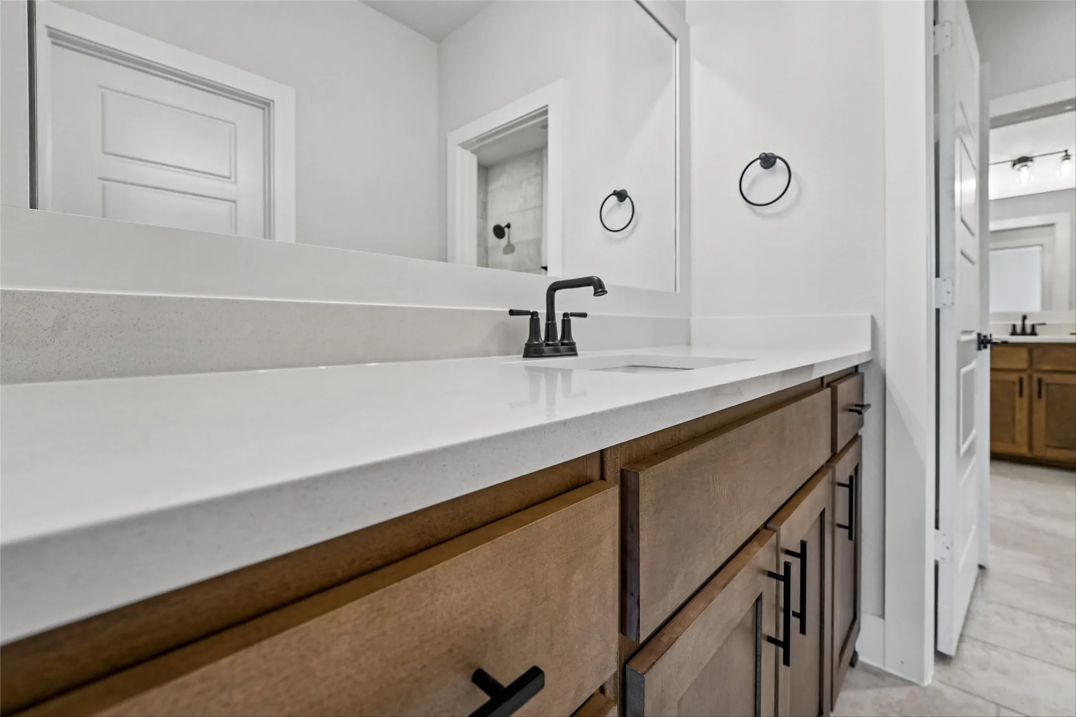 Bathroom vanity featuring a white countertop, undermount sink, and matte black faucet