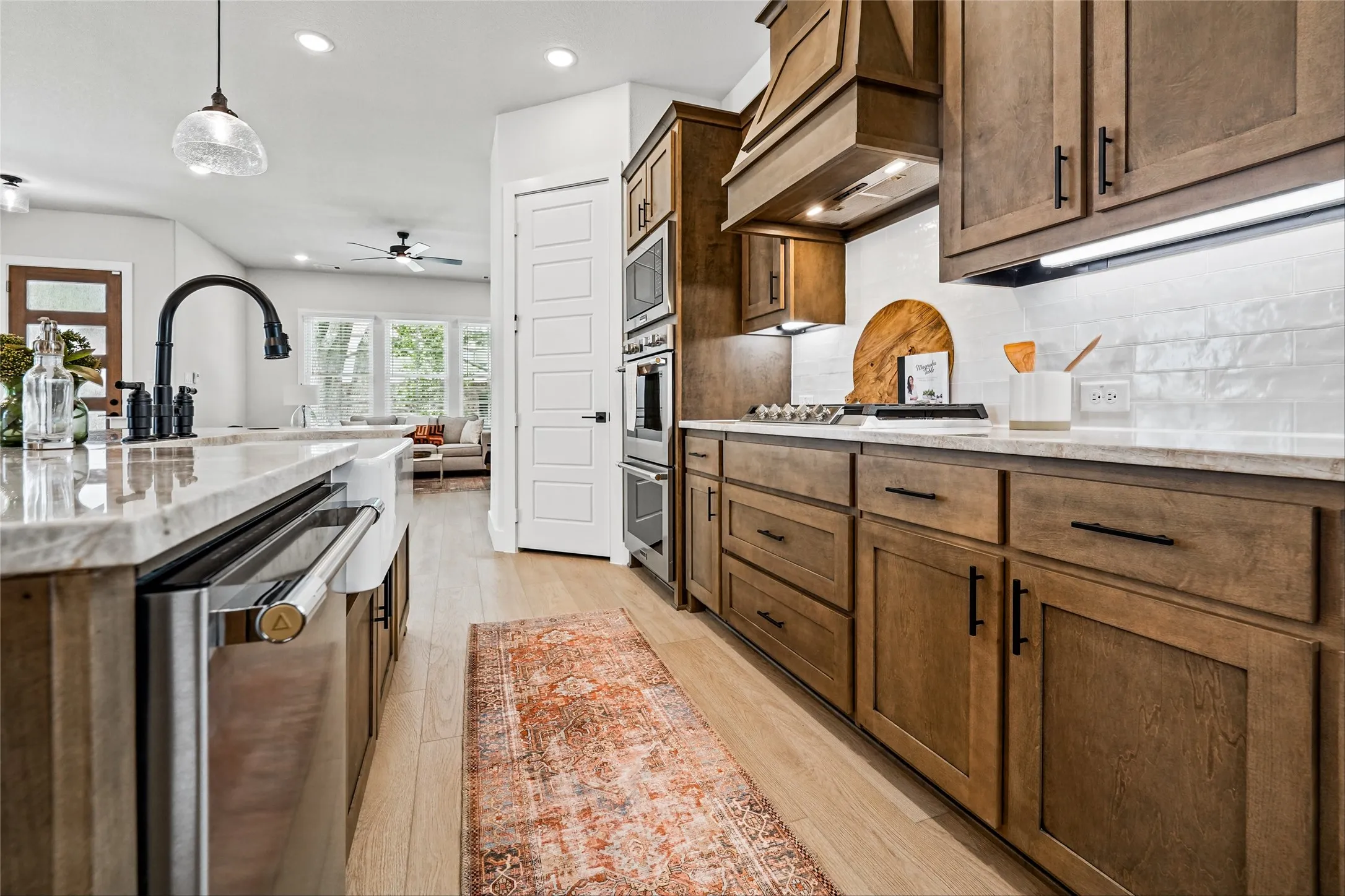 Kitchen featuring wood-finish cabinetry, stainless steel appliances, a white subway tile backsplash, and light-toned countertops