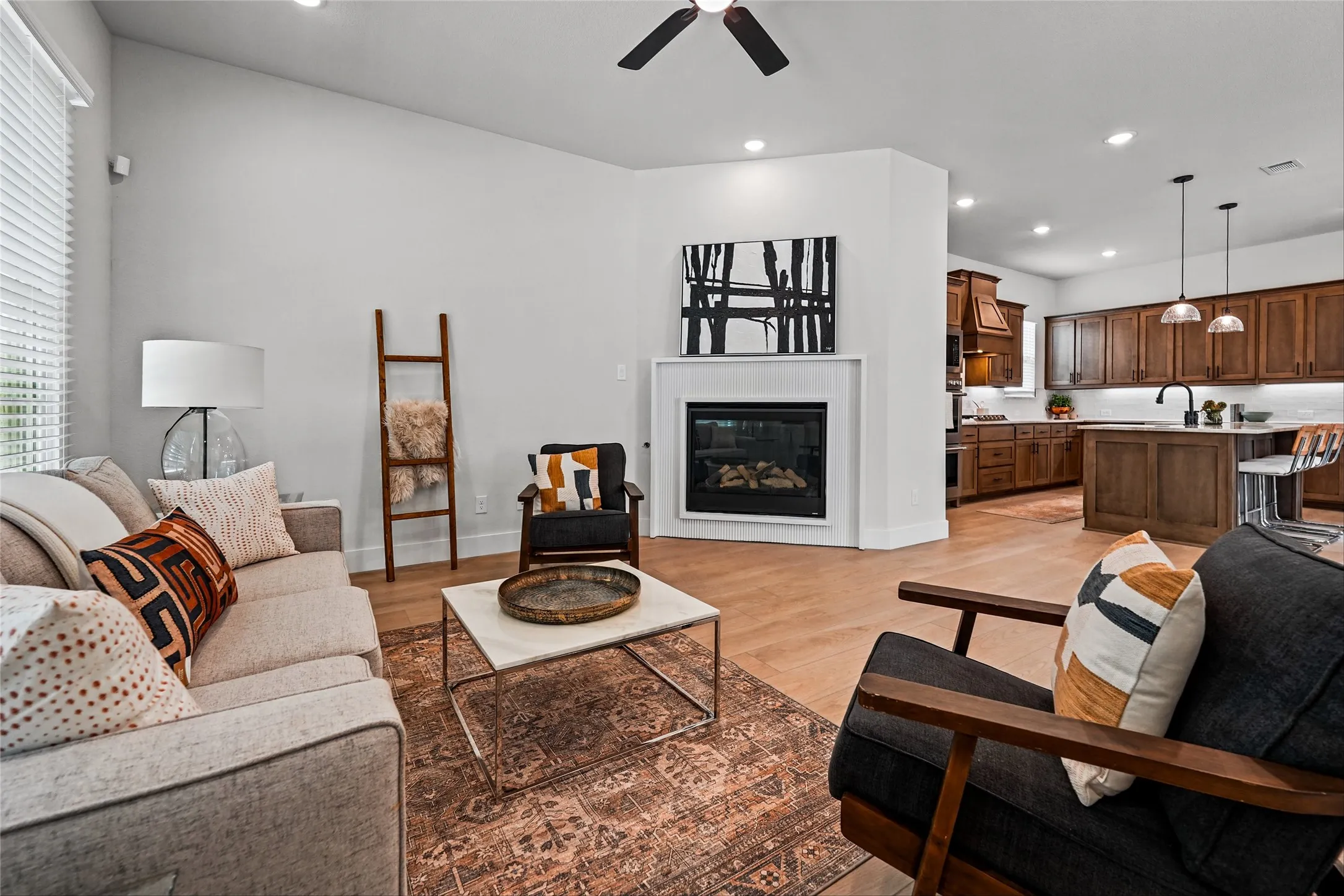 Open-concept living area with wood-finish flooring, a contemporary fireplace, and recessed lighting