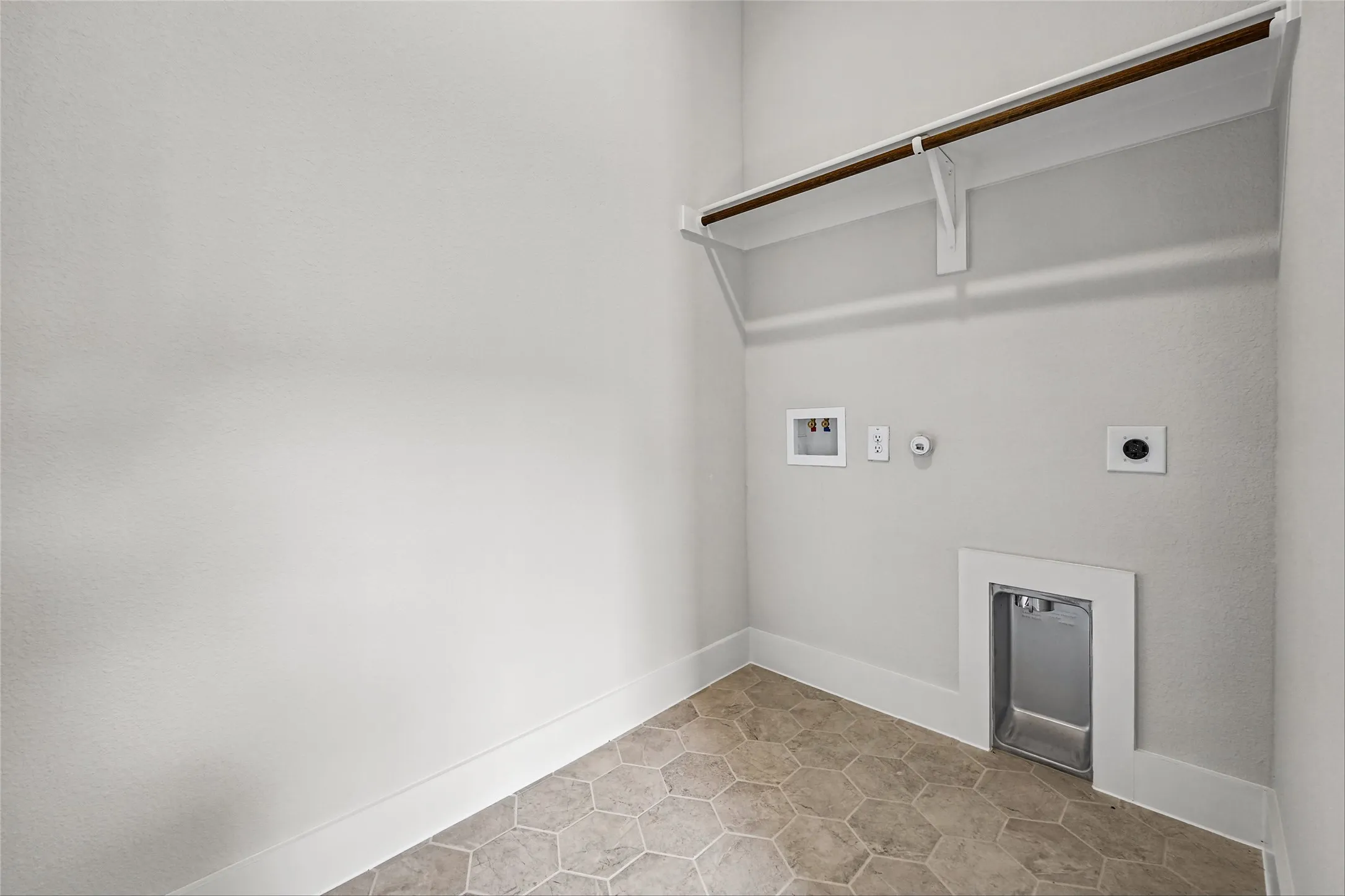 Hexagonal floor tiling, white walls, and a built-in hanging rod with shelving