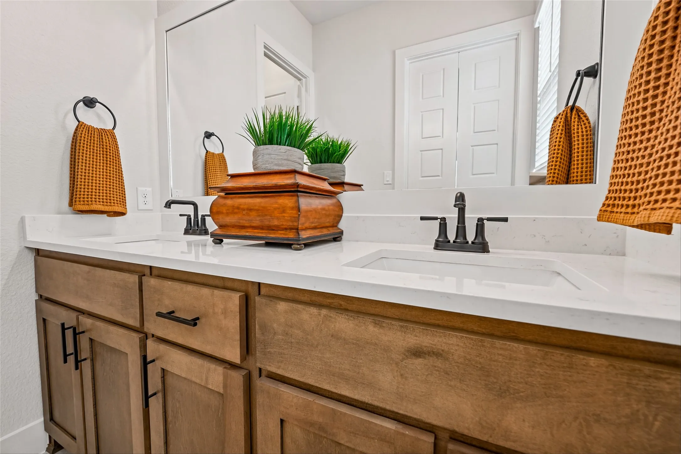 Dual vanity with integrated rectangular sinks, white countertop, wood-finish cabinetry, and matte black fixtures