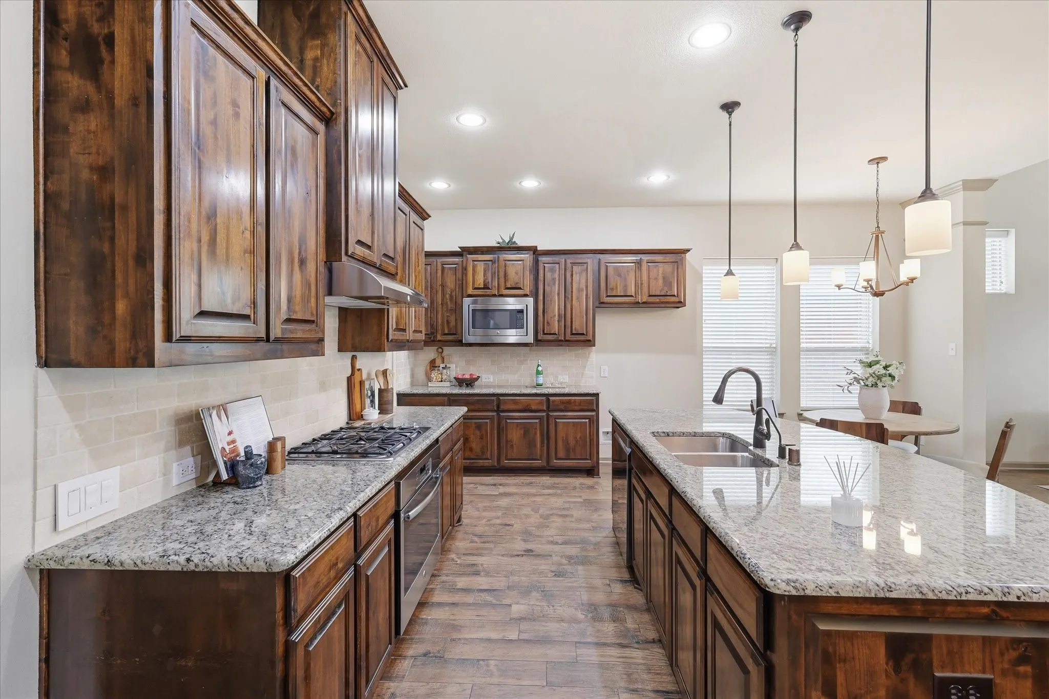 Kitchen featuring wood-finish cabinetry, granite countertops, tile flooring, stainless steel appliances, and recessed lighting