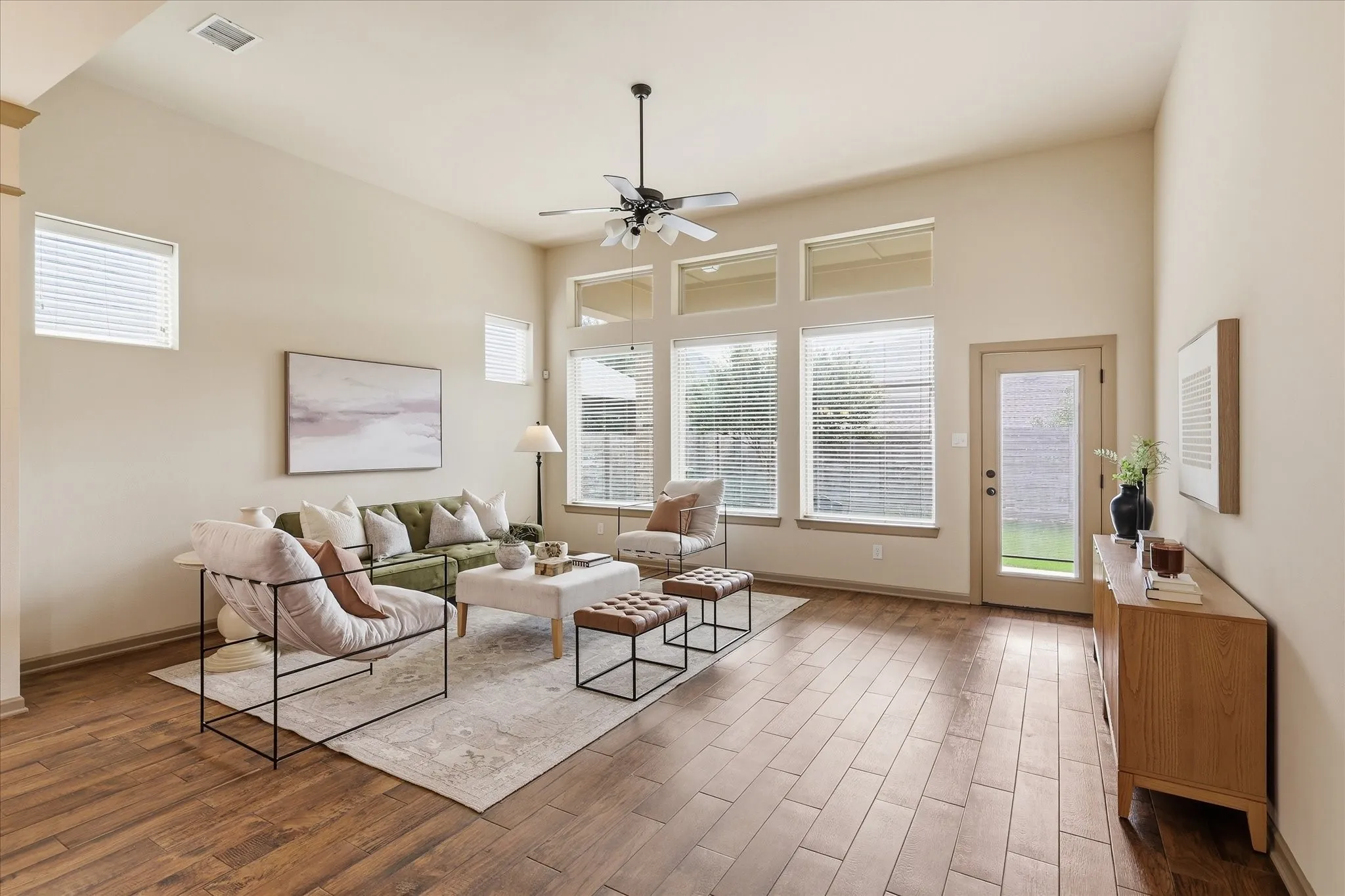 Spacious living area featuring wood-like tile flooring, vaulted ceilings, and a ceiling fan