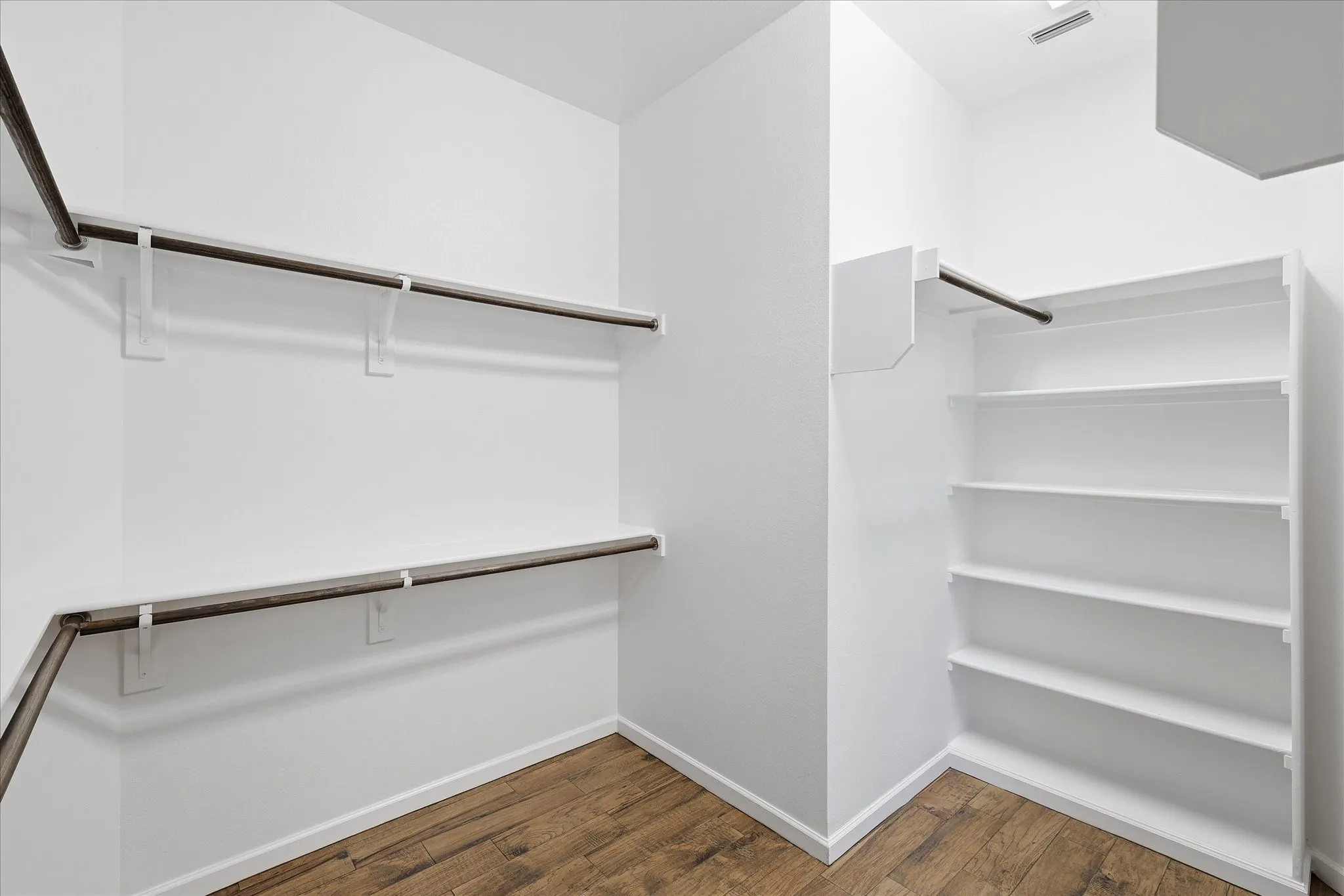 Walk-in closet featuring multiple hanging rods, and integrated shelving units